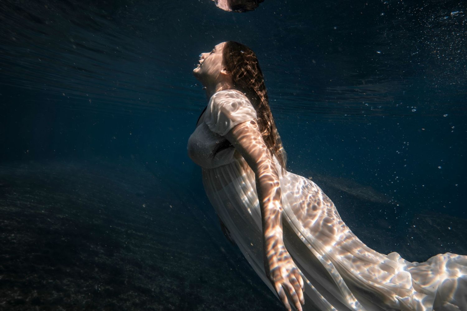 Cinematic underwater photo, in a documentary style, magical underwater photoshoot. Destination Elopement, maternity underwater photographer