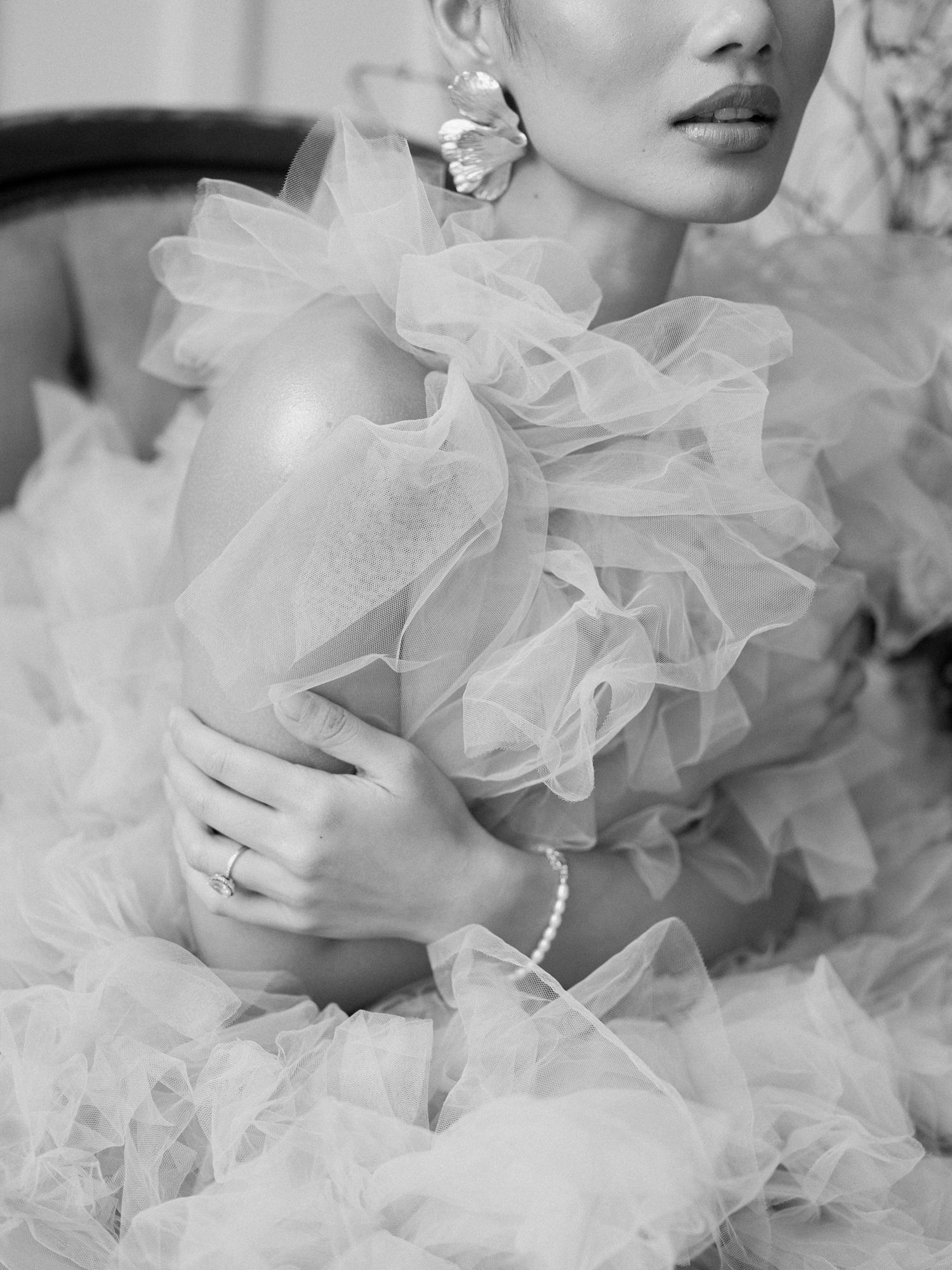 Ethereal black and white fashion photograph featuring delicate tulle ruffles, a pearl bracelet and statement silver earring.