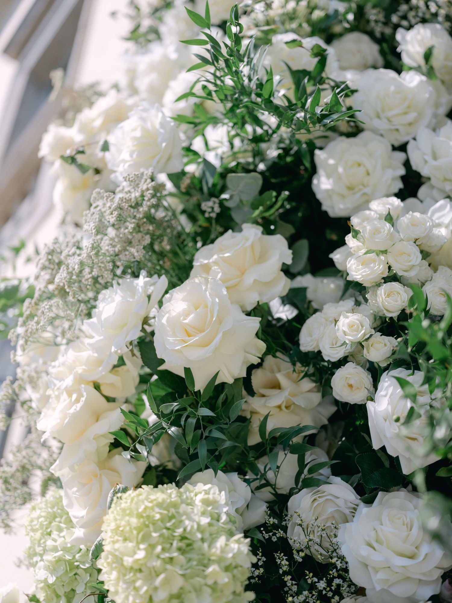 Lush arrangement of white roses, hydrangeas, and greenery creating an elegant floral display.