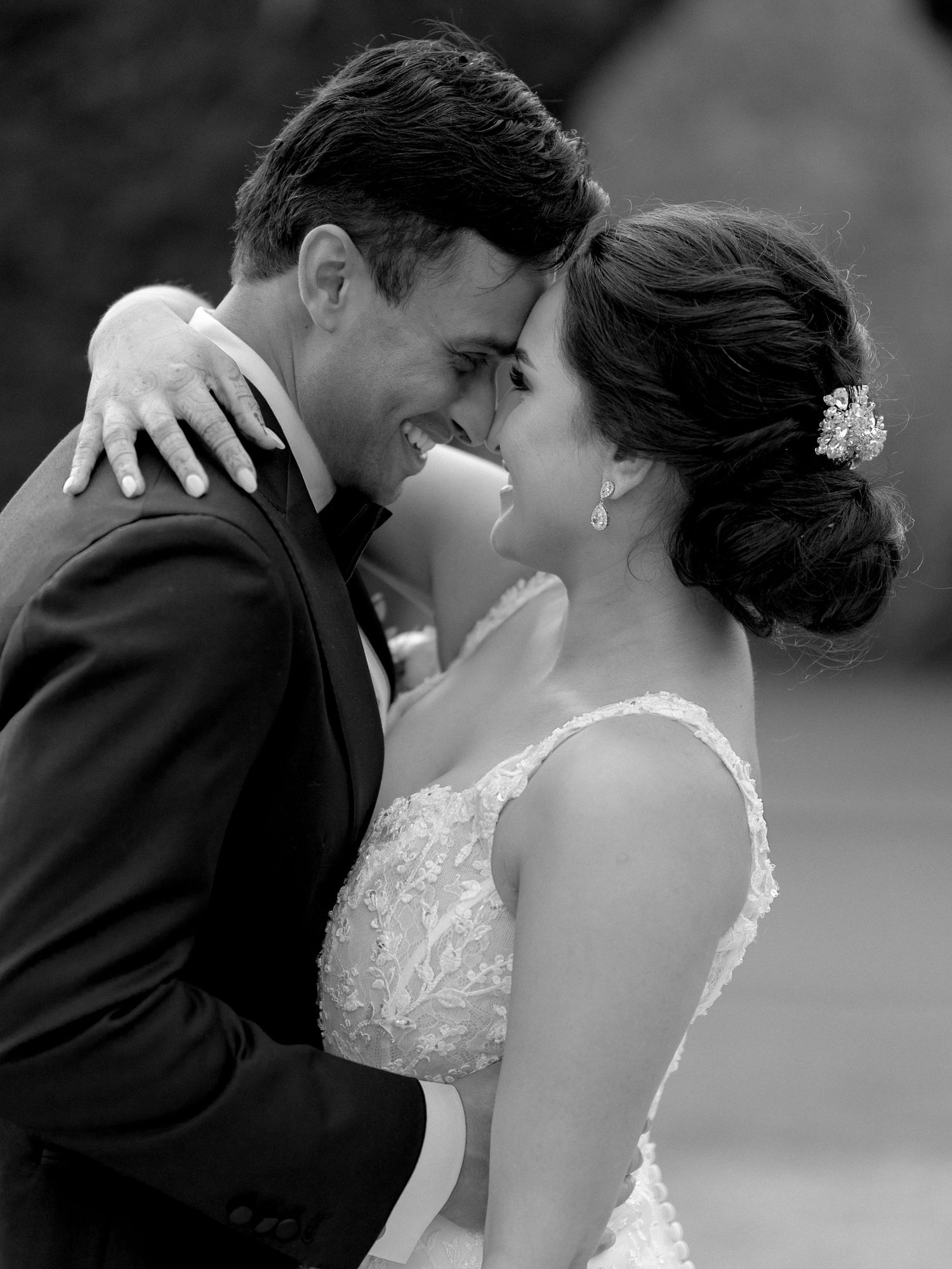 Black and white photo of a smiling bride and groom in an intimate embrace on their wedding day.