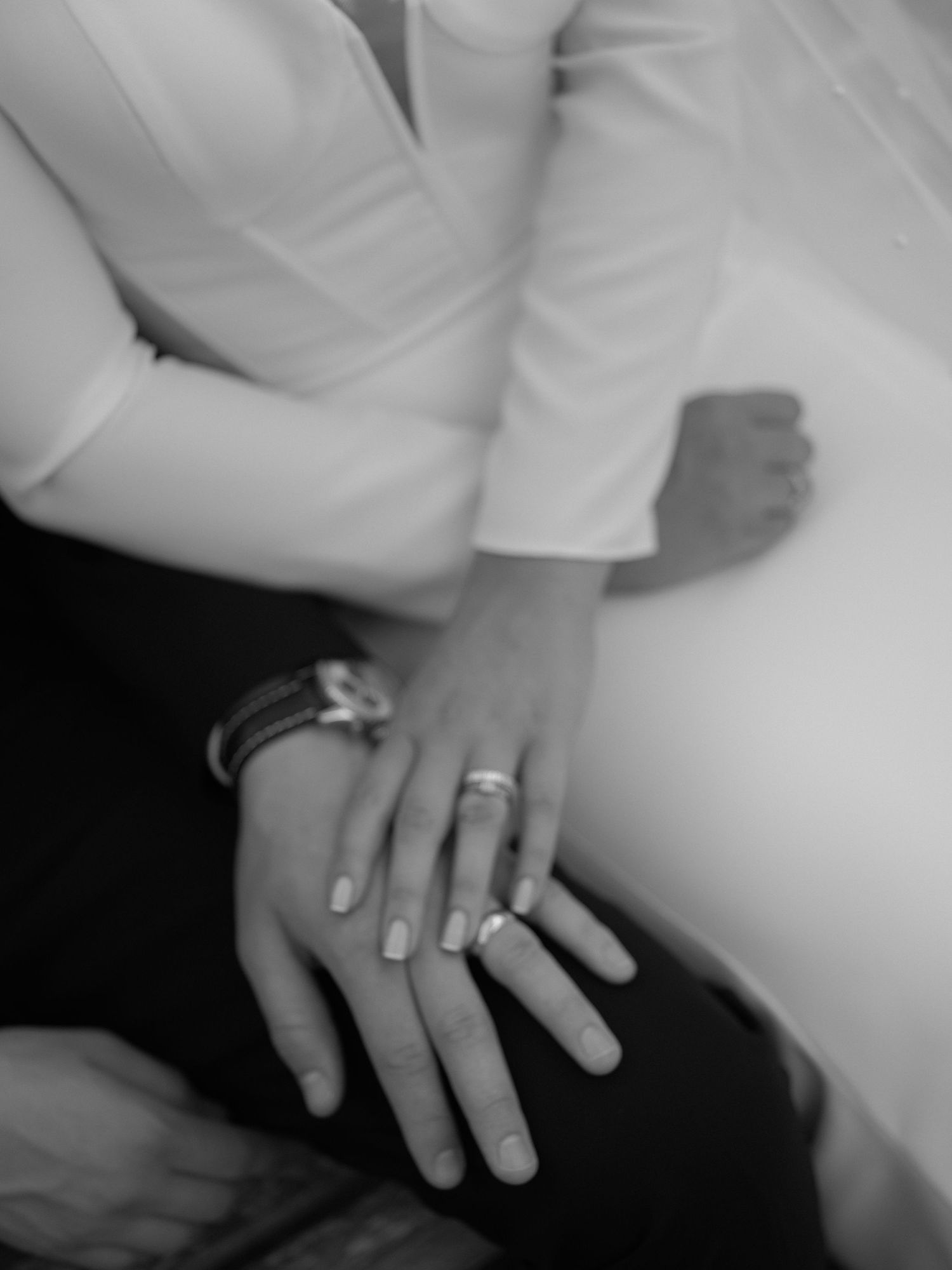 Black and white photo of a couple's hands showing wedding rings, symbolizing love and commitment.