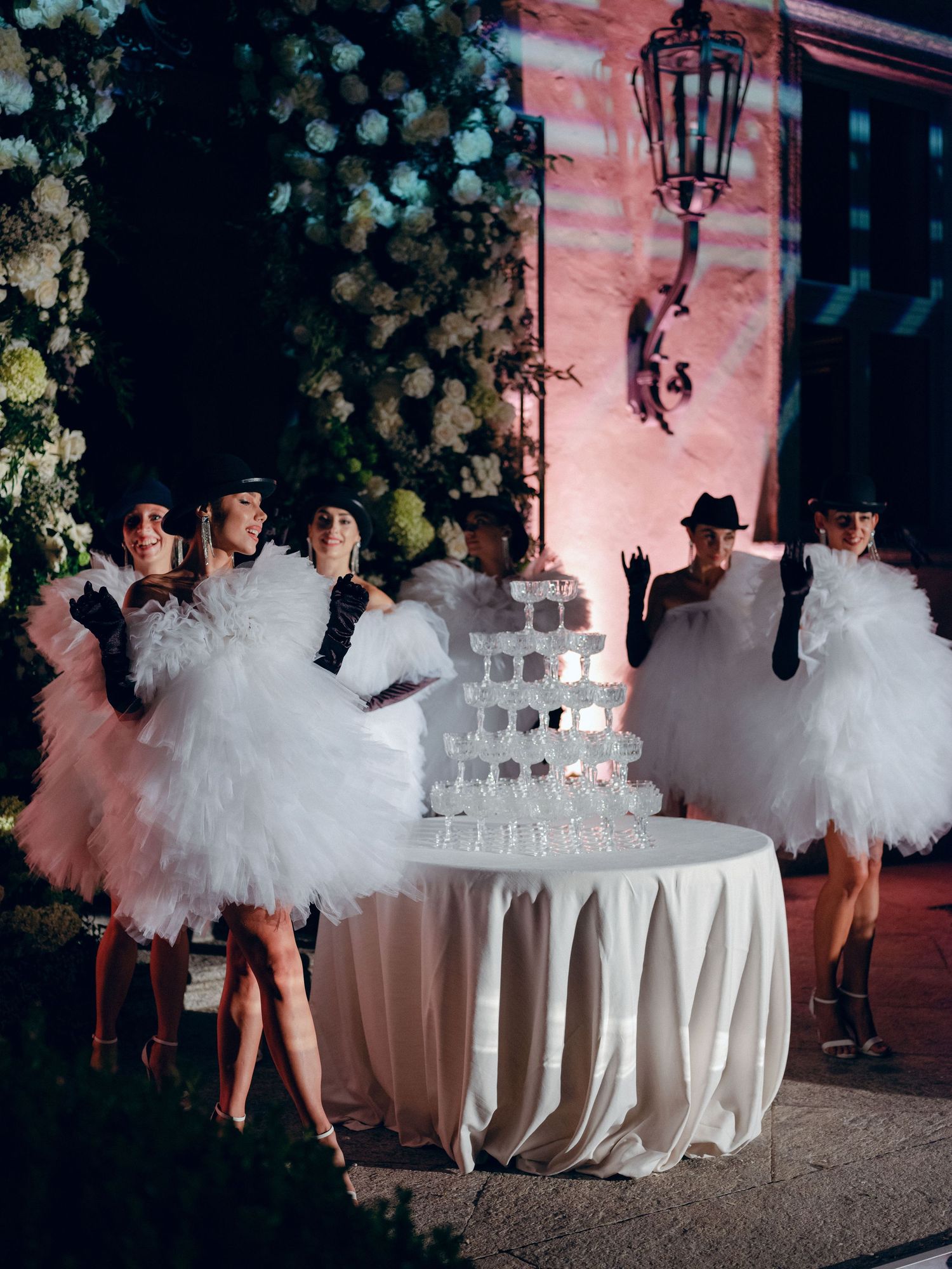 A sequence of photos showing a tulle-skirted figure dancing around an elegant white-clothed table with stacked glasses.