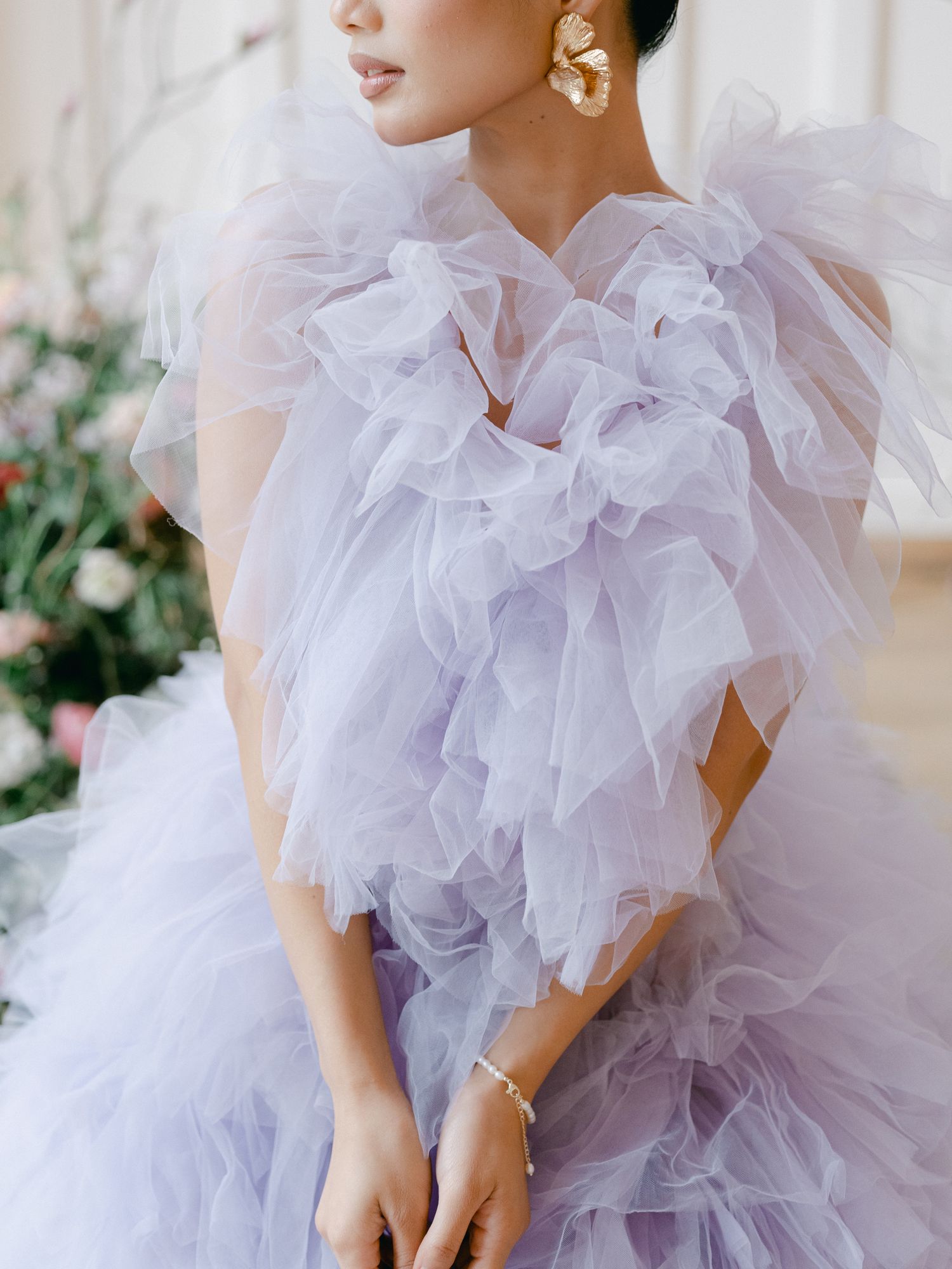 Ethereal lavender tulle gown with dramatic ruffled details and statement pearl earrings creates romantic bridal look.