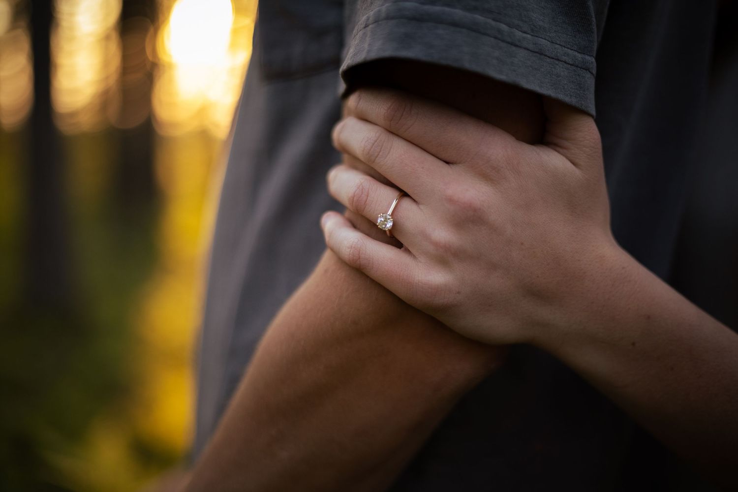 Silhouetted hands holding each other against a warm sunset background.