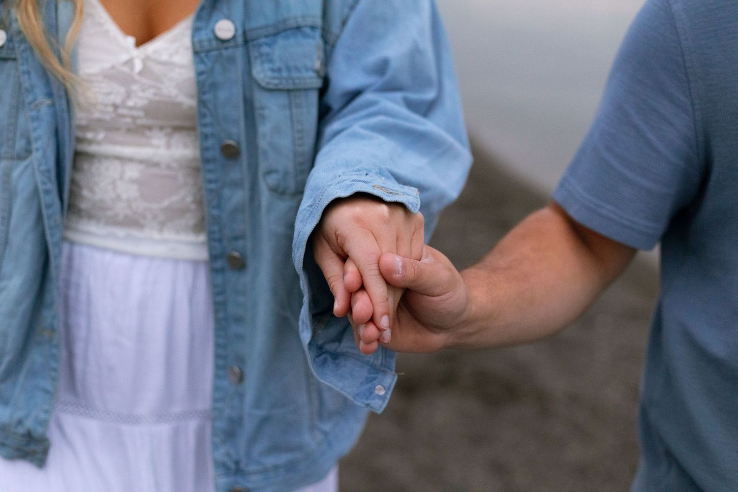 A group of people wearing denim jackets and white dresses stand together in a casual setting.