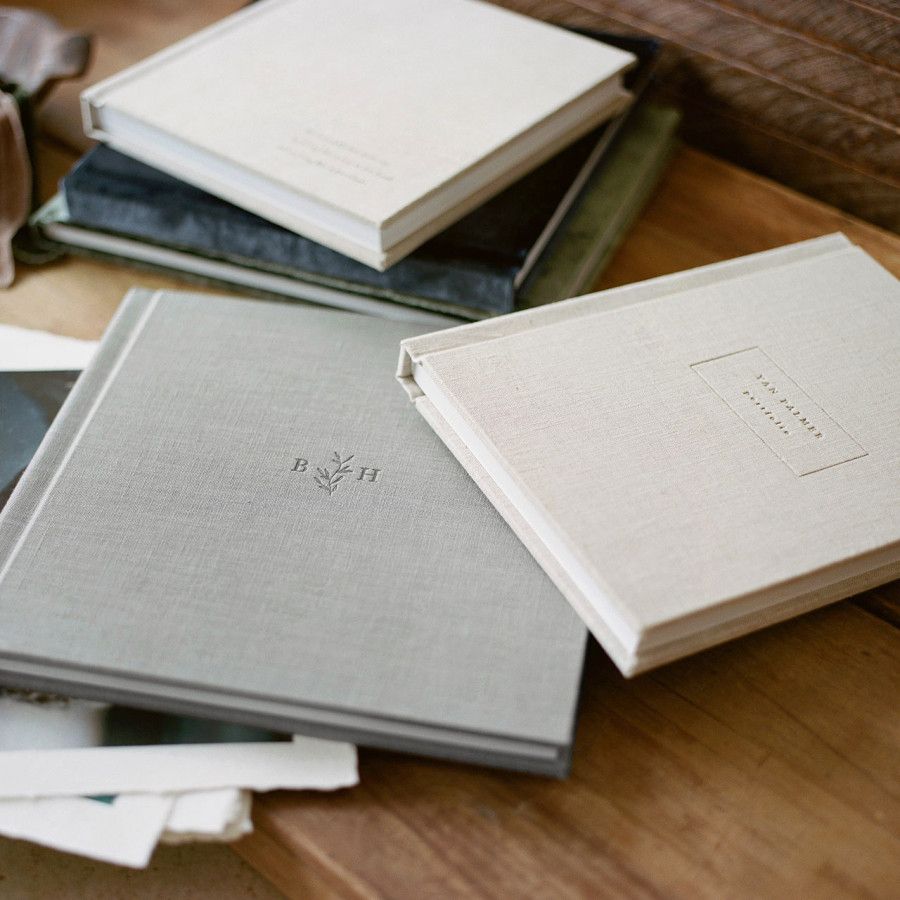 Multiple white hardcover books arranged on a wooden surface in an artistic composition.