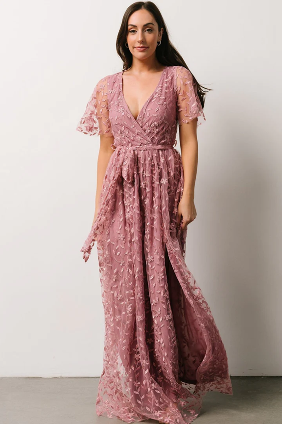 Dusty rose lace maxi dress with flutter sleeves and empire waist shown in studio setting.