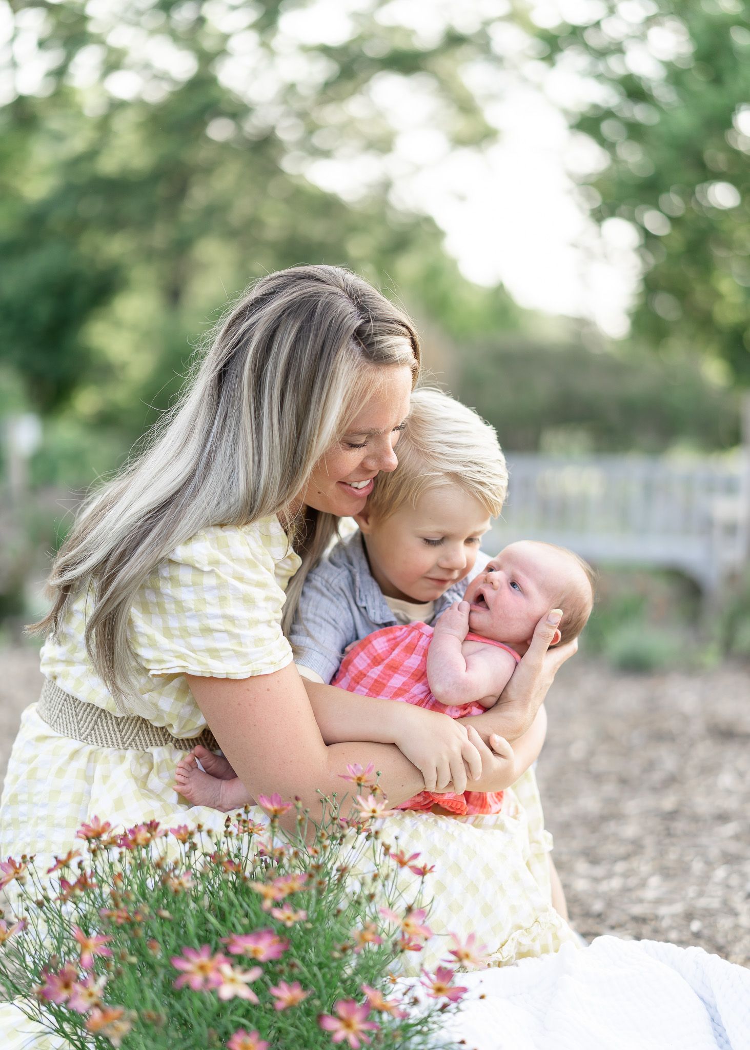 A tender moment captured in a garden setting with pink wildflowers blooming in the foreground.