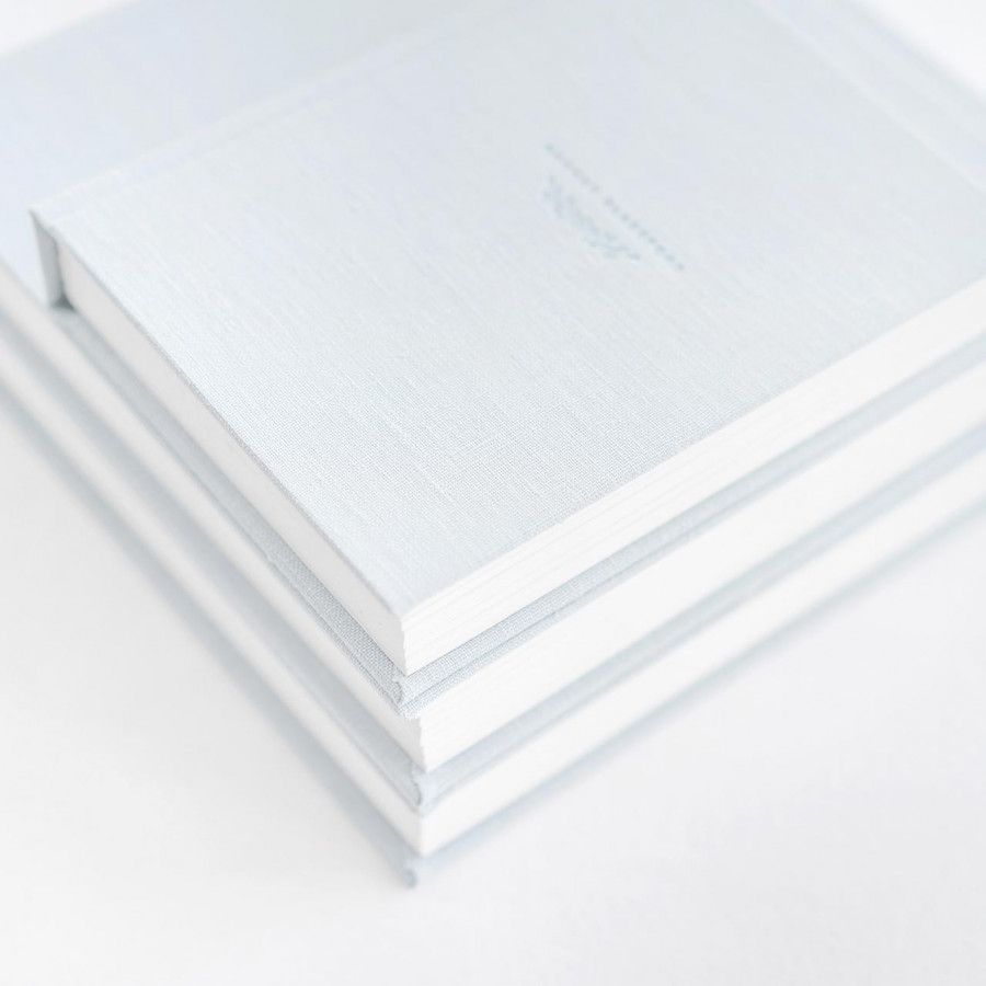 Stack of white paper notebooks with minimalist design against light background.