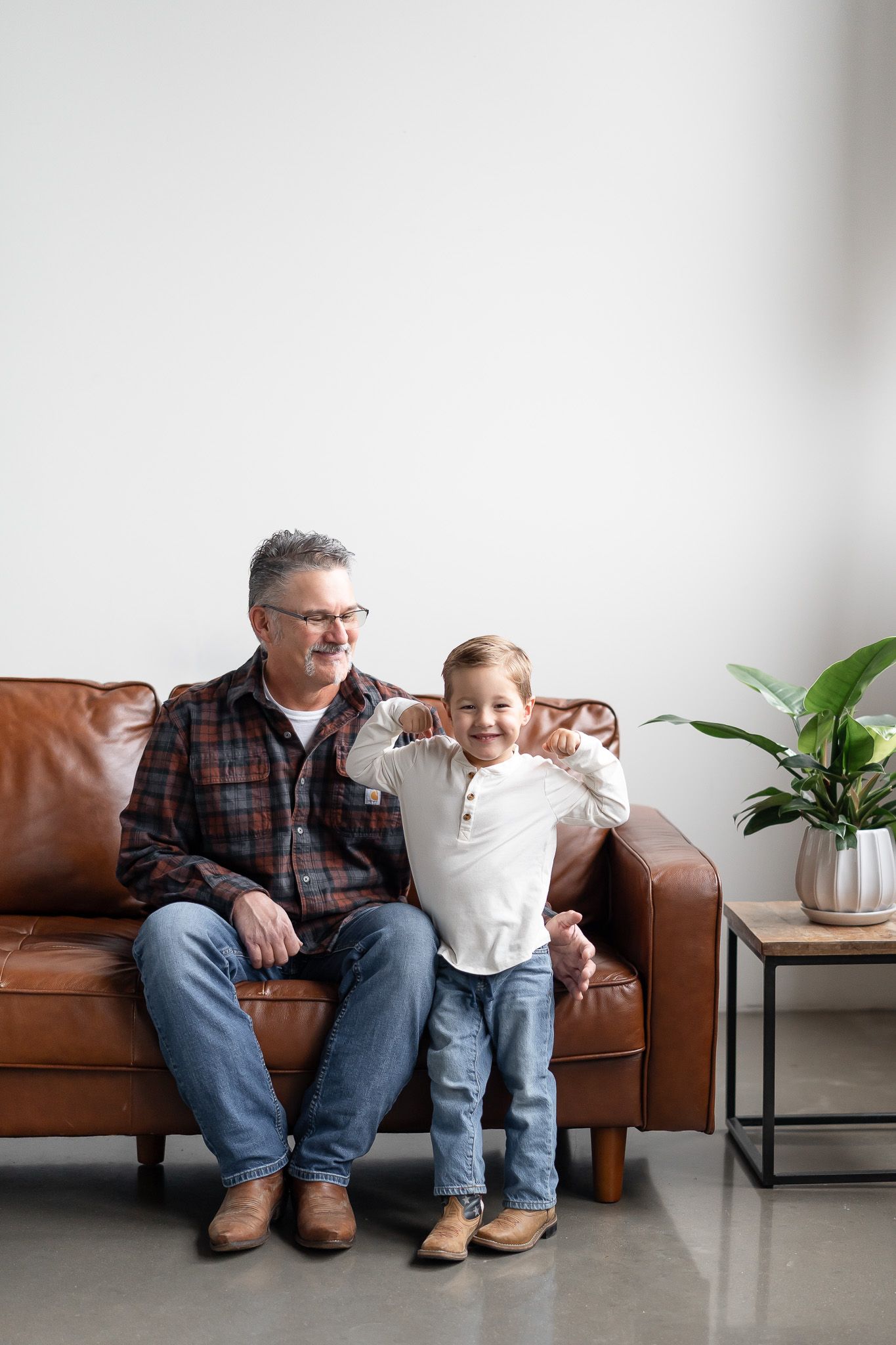 A series of four photos showing a person sitting with a child on a brown leather couch next to a houseplant.