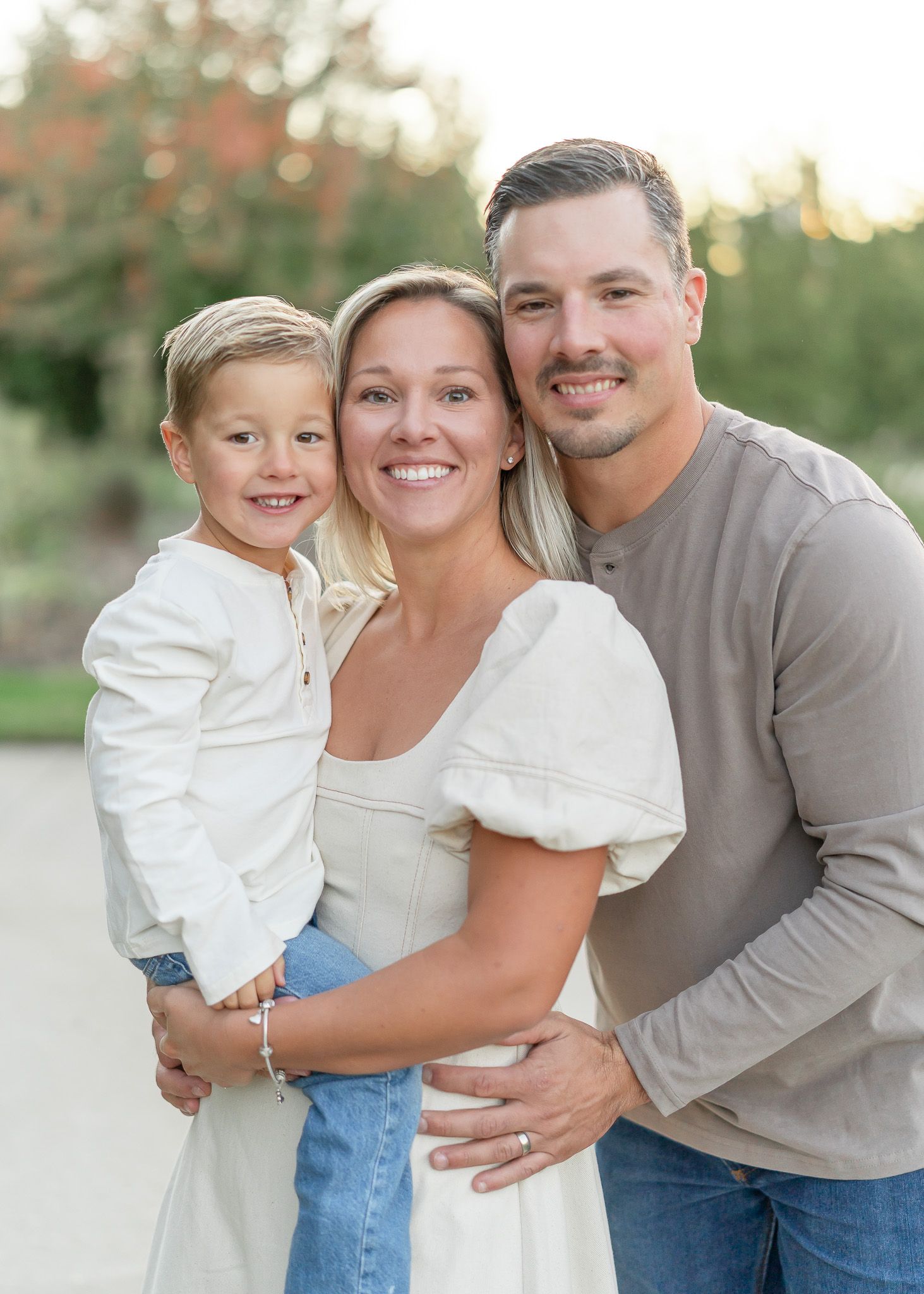 A family poses together outdoors during a photo session at sunset in a park setting.