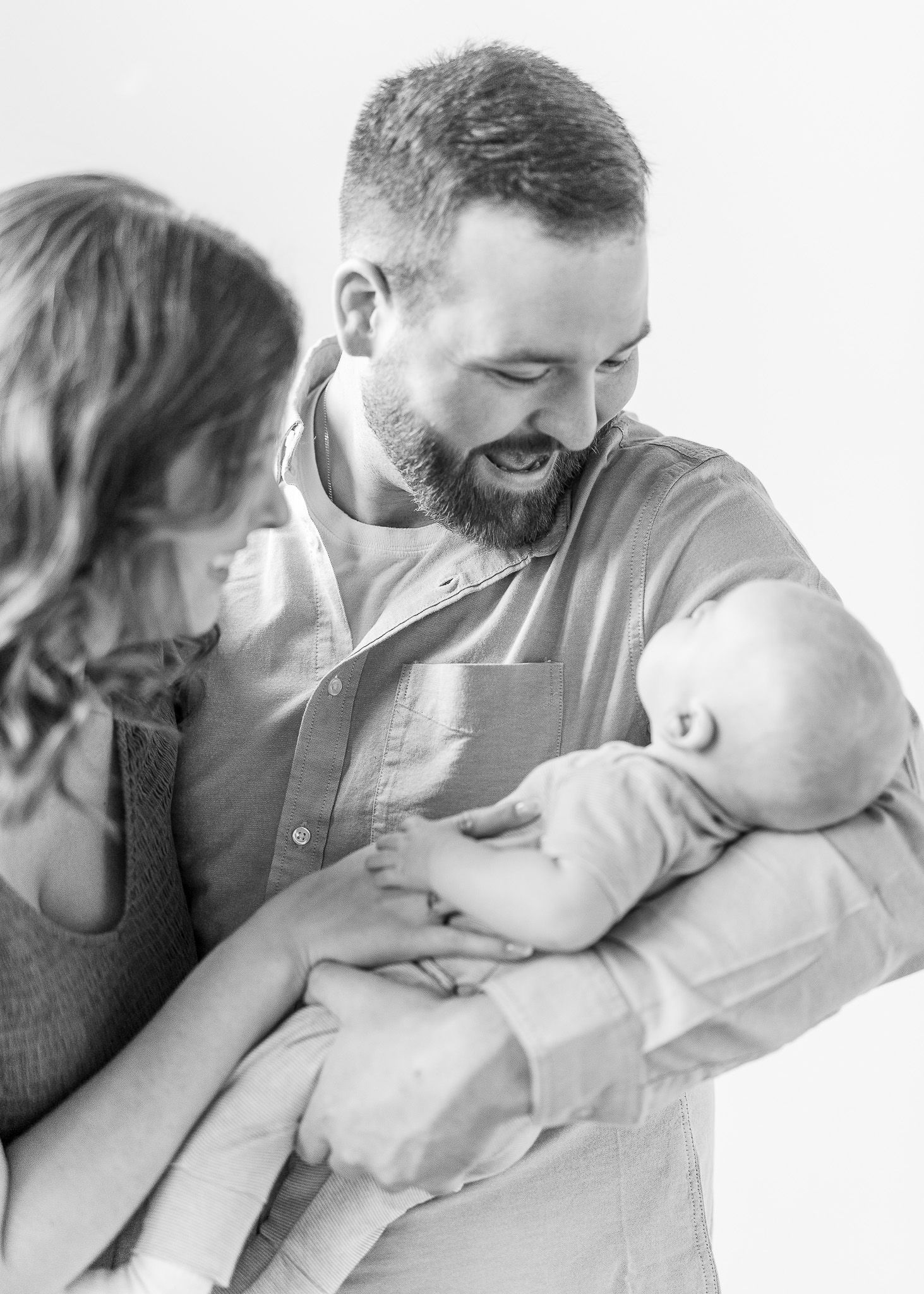 Black and white photo series showing tender family moments with a newborn baby in a minimalist style.