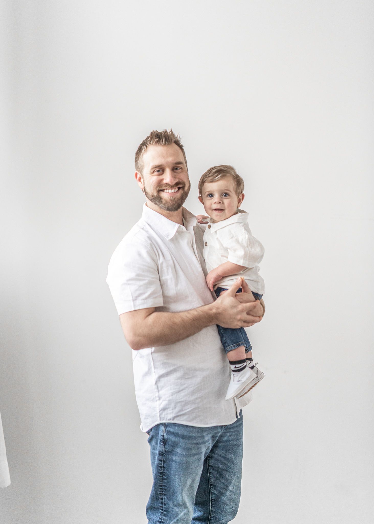 A parent in a white shirt and jeans holds and plays with a small baby in a series of four candid photos.