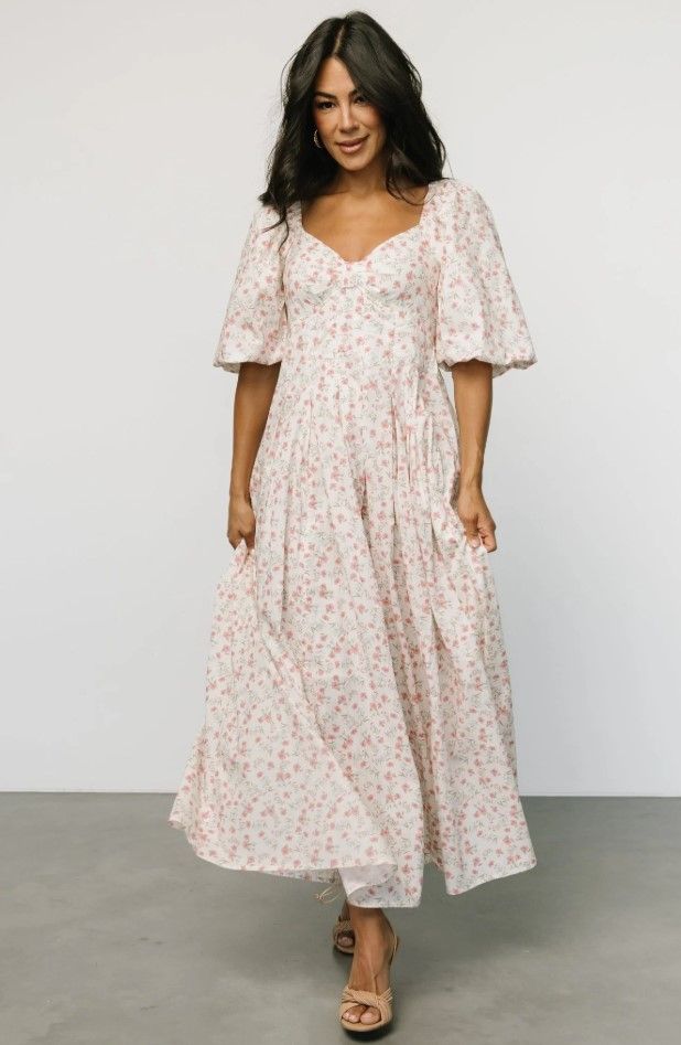 Pink floral print midi dress with puff sleeves modeled against white background.