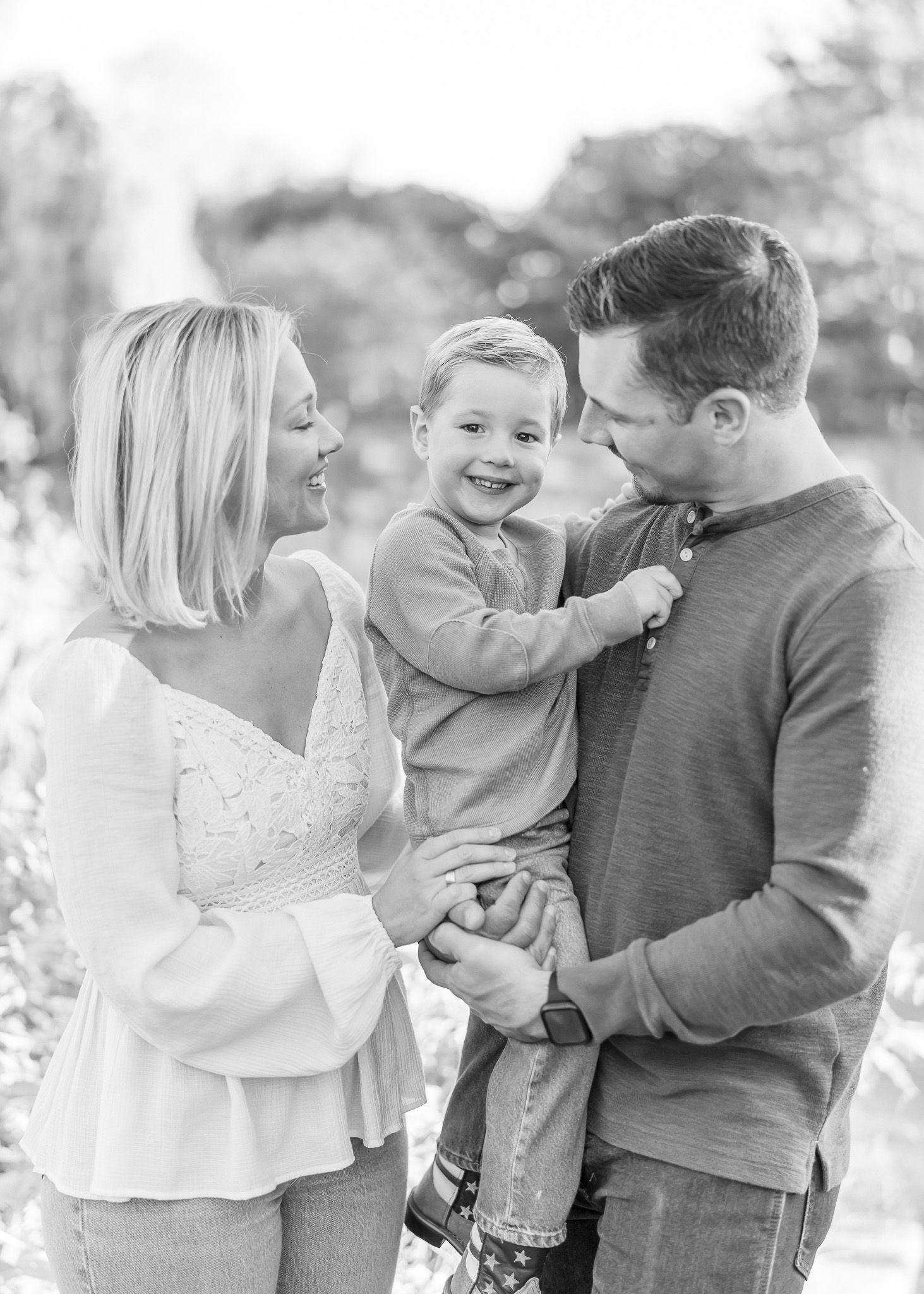 A joyful family moment captured in black and white showing affectionate interaction outdoors.