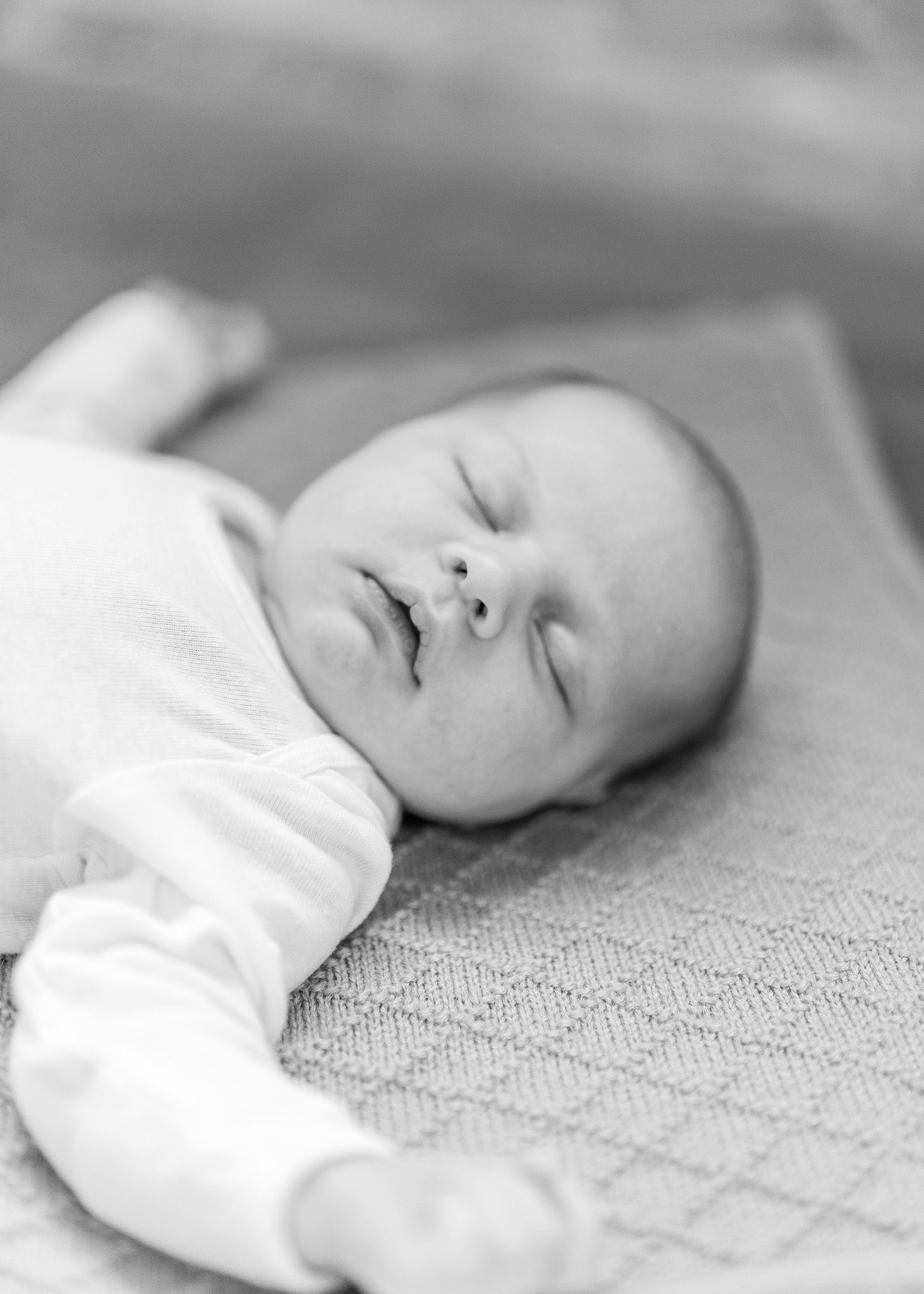A peaceful sleeping baby lies on a textured blanket in a series of black and white photographs.
