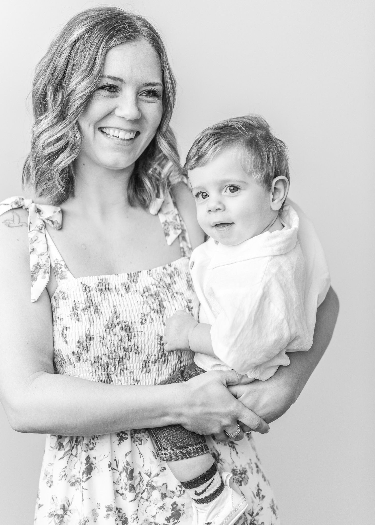 Black and white photo series showing tender moments between a parent and young child in matching floral outfits.