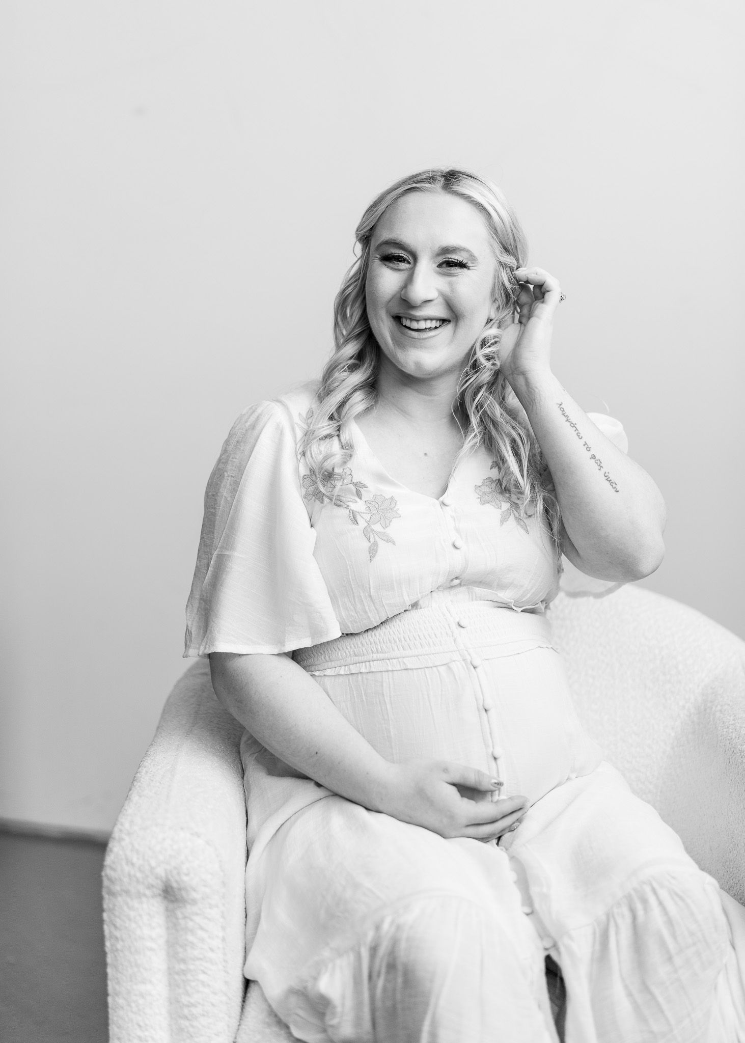 A series of black and white portraits showing someone in white clothing sitting and posing on a white chair.