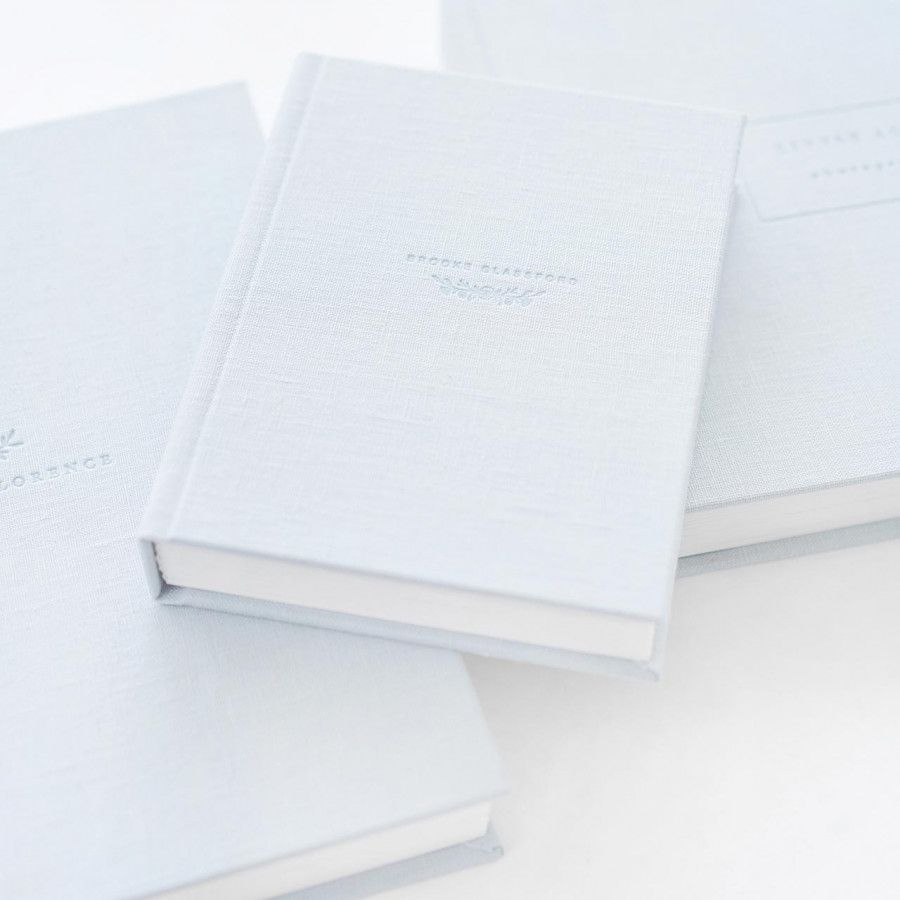 Minimalist white hardcover books arranged in a clean, monochromatic composition on white surface.