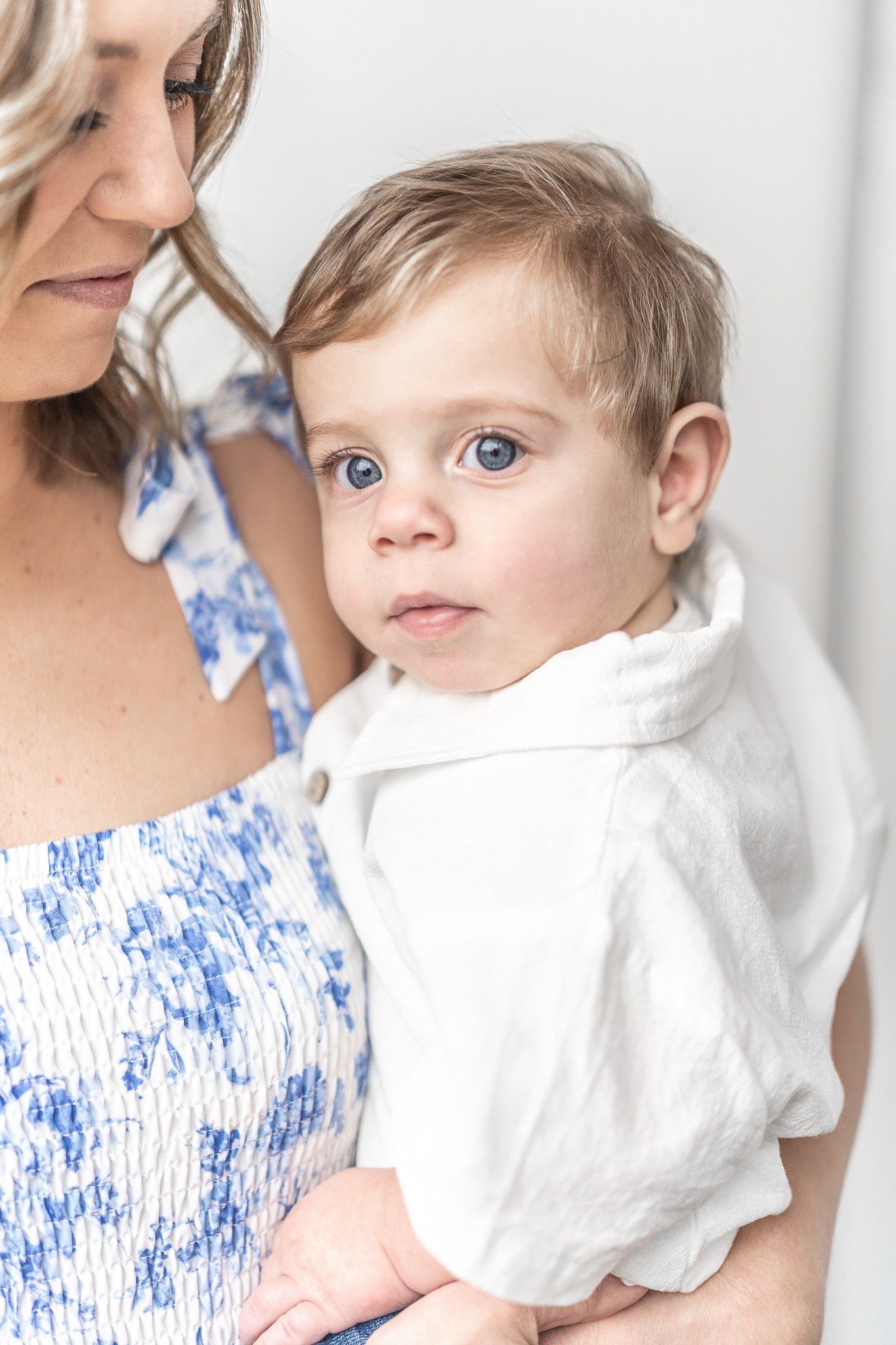 Parent and child in blue and white outfits pose against white background.