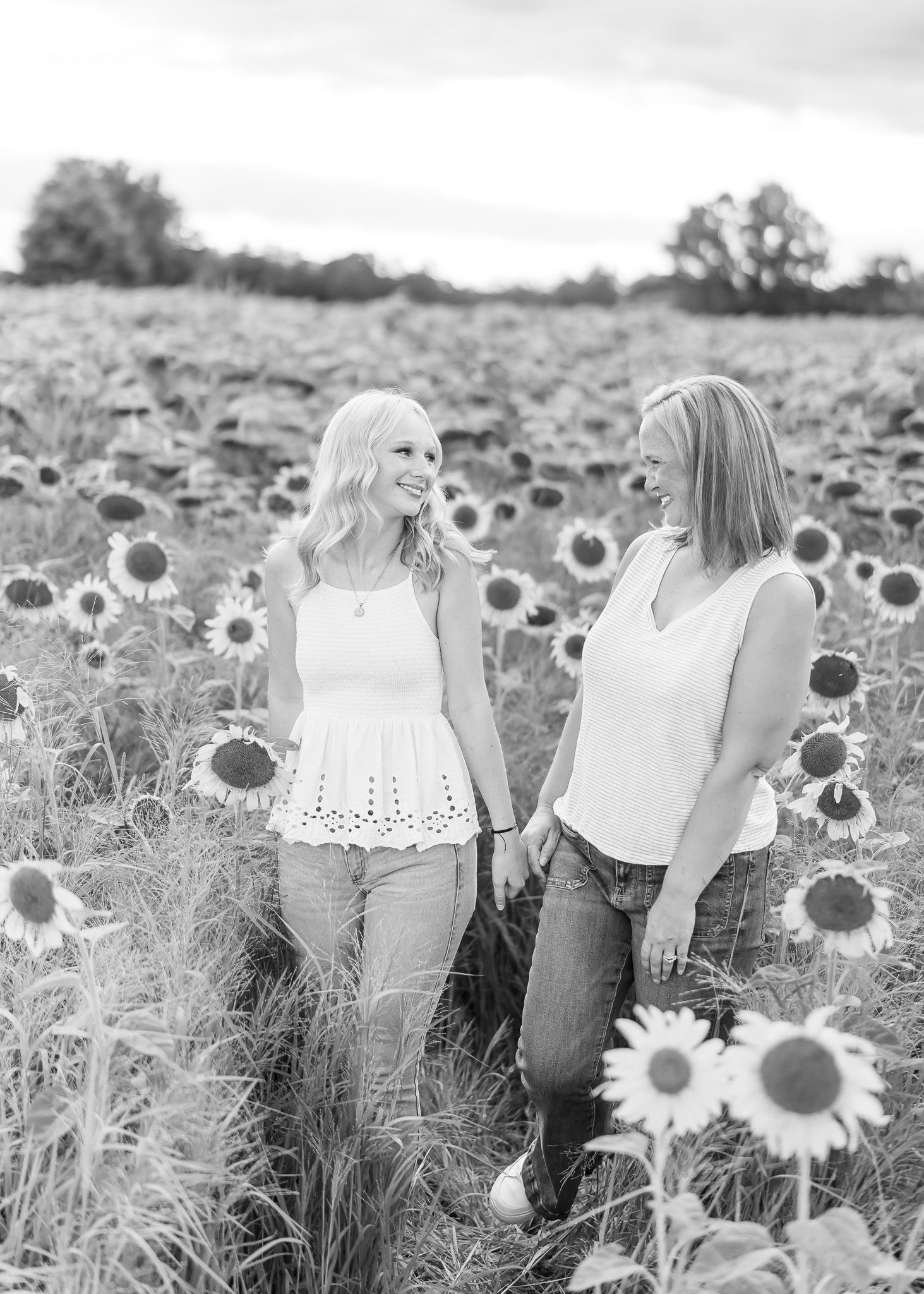 Two people sit together in a dreamy black and white sunflower field on a summer afternoon.