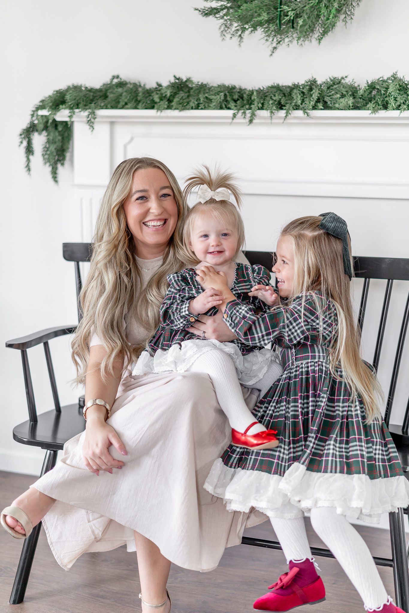 Holiday family photos showing playful moments on a black bench with festive greenery decor.