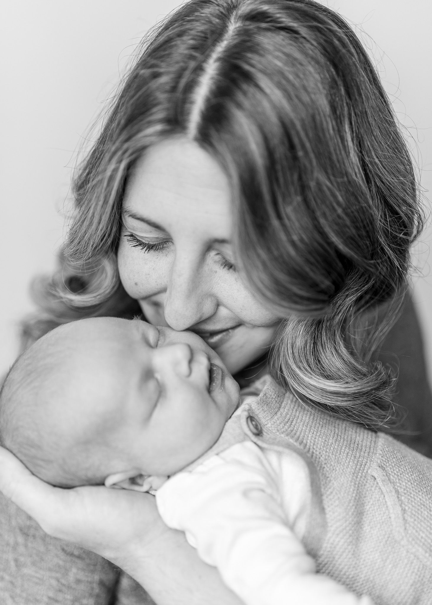 A series of black and white photos showing a tender romantic kiss between two people in soft lighting.