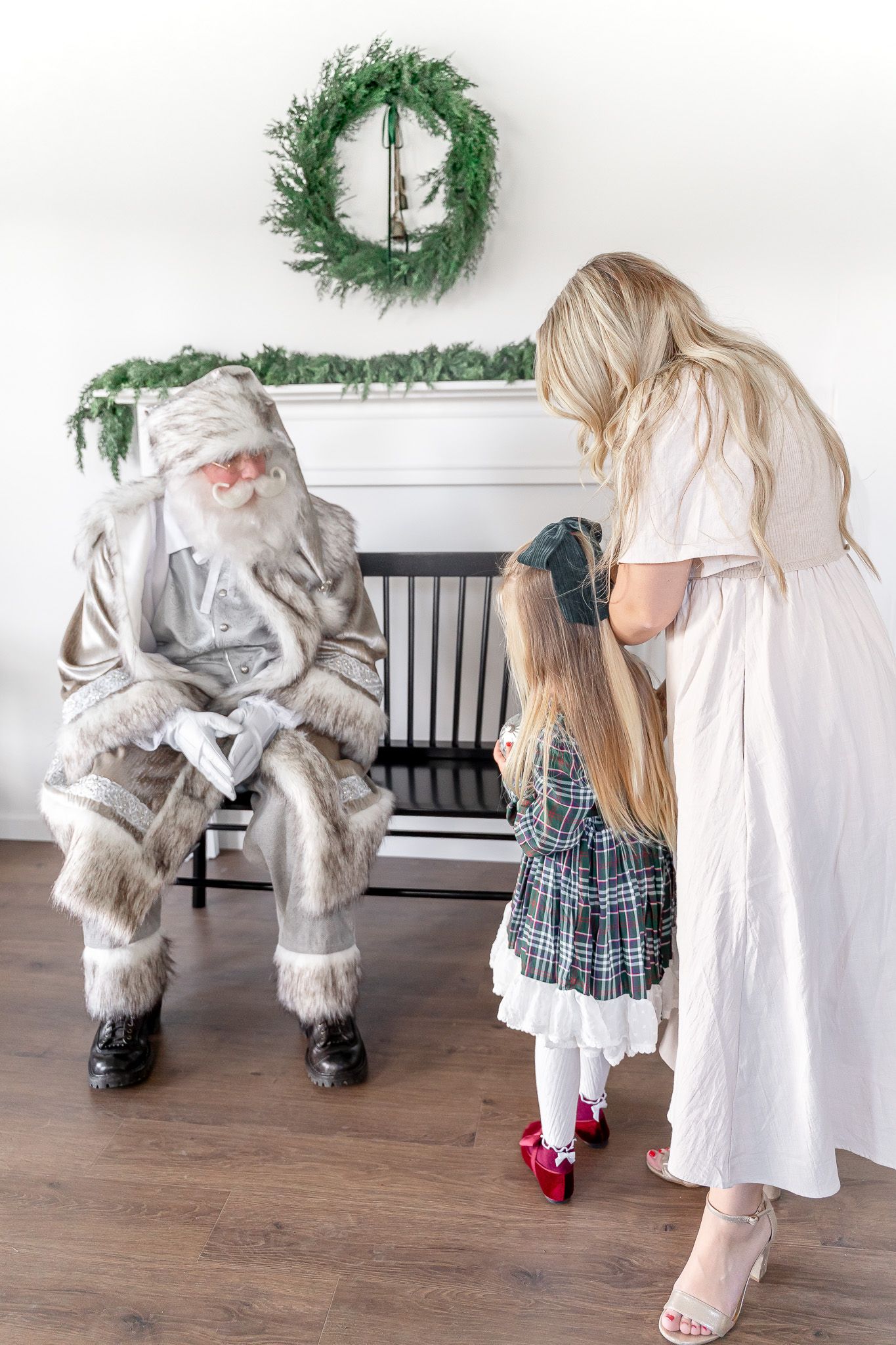 Holiday scene with black bench, evergreen wreath, and festive clothing details.