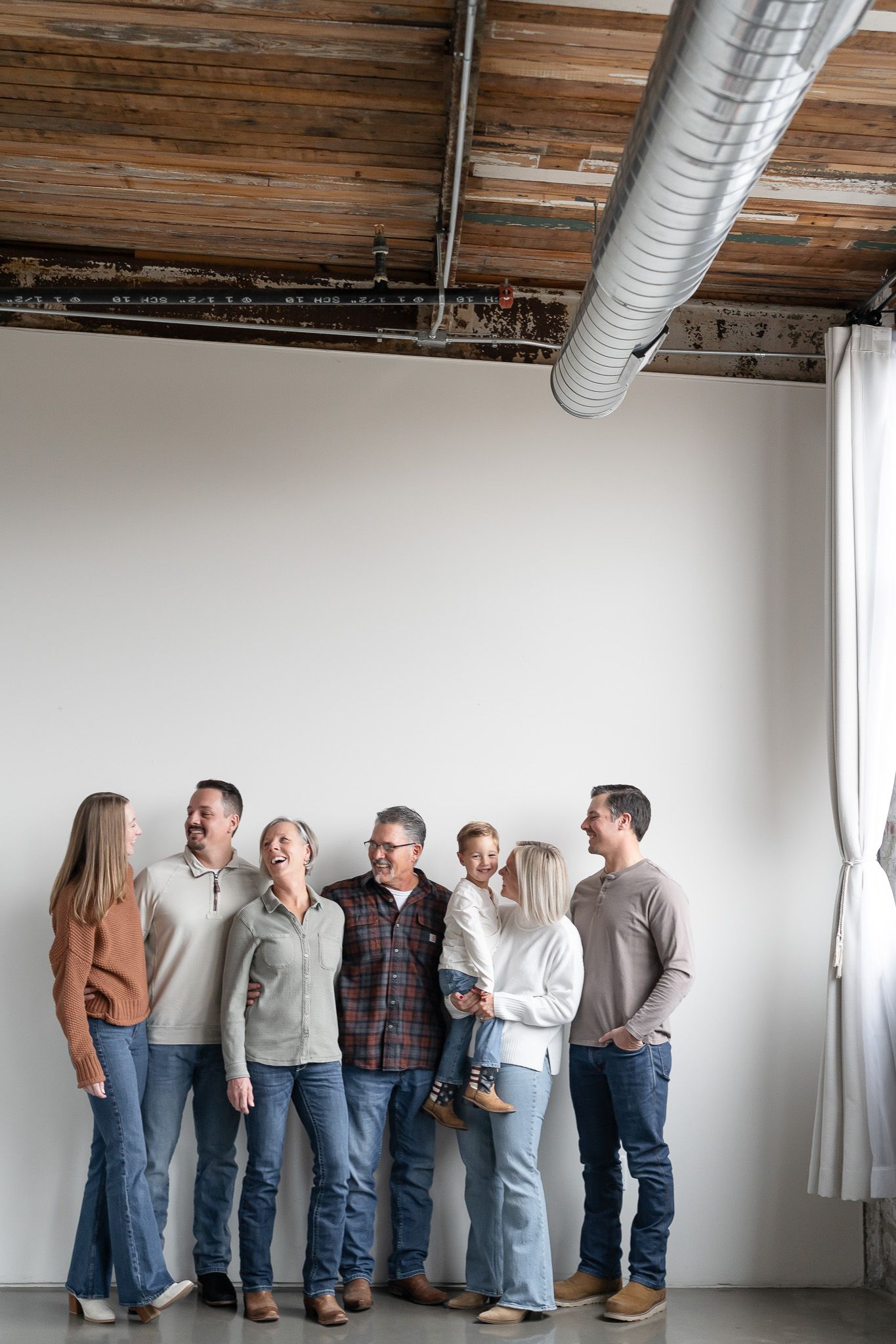 A panoramic view of people standing in a line against a white wall with exposed wooden beams overhead.