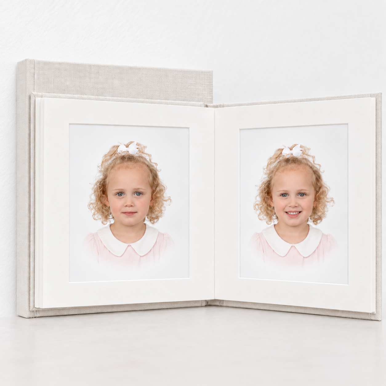 Twin girls portrait displayed in an open white matted photo album with two matching school photos side by side.