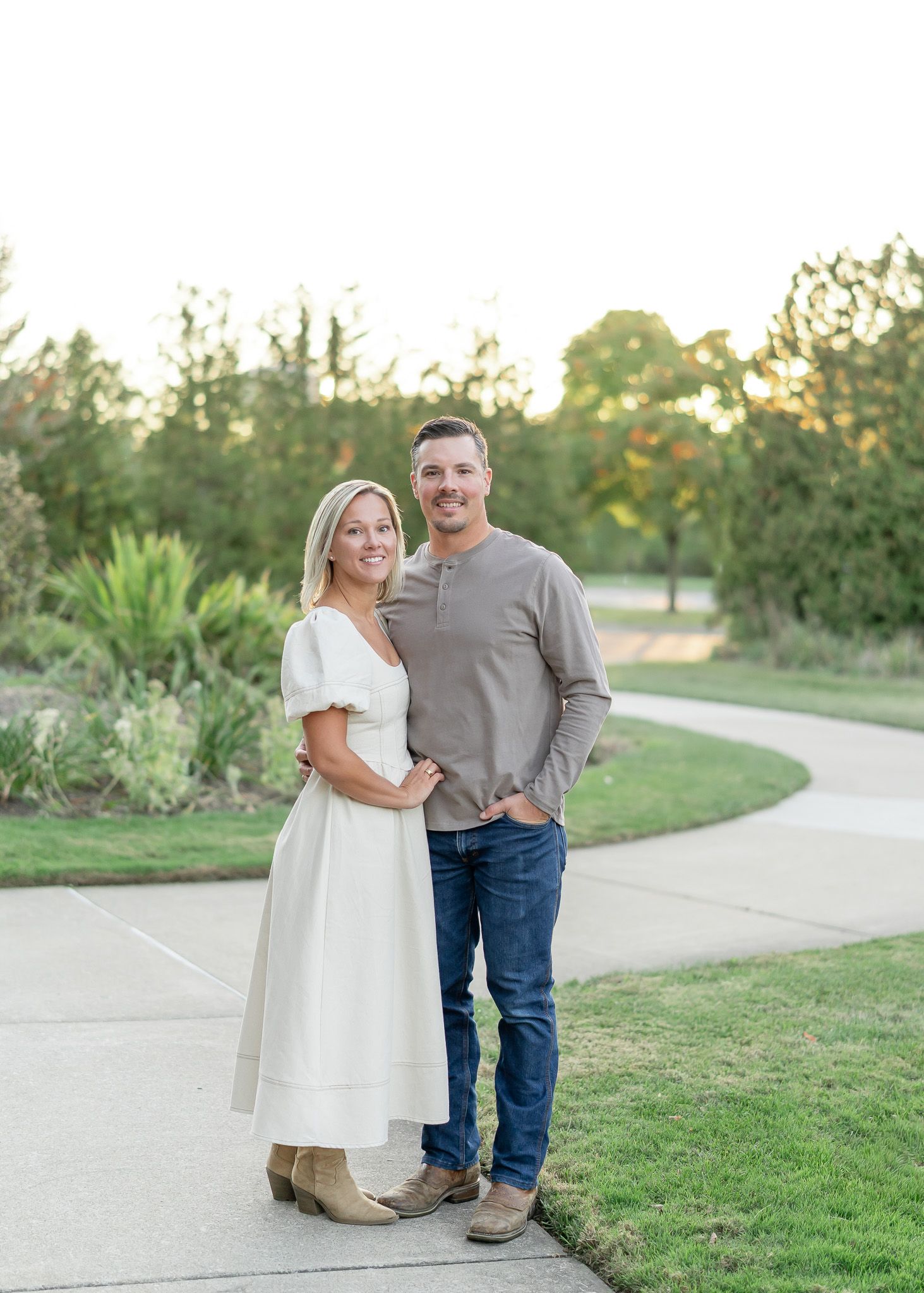 A couple shares a romantic moment on a winding garden path during golden hour.