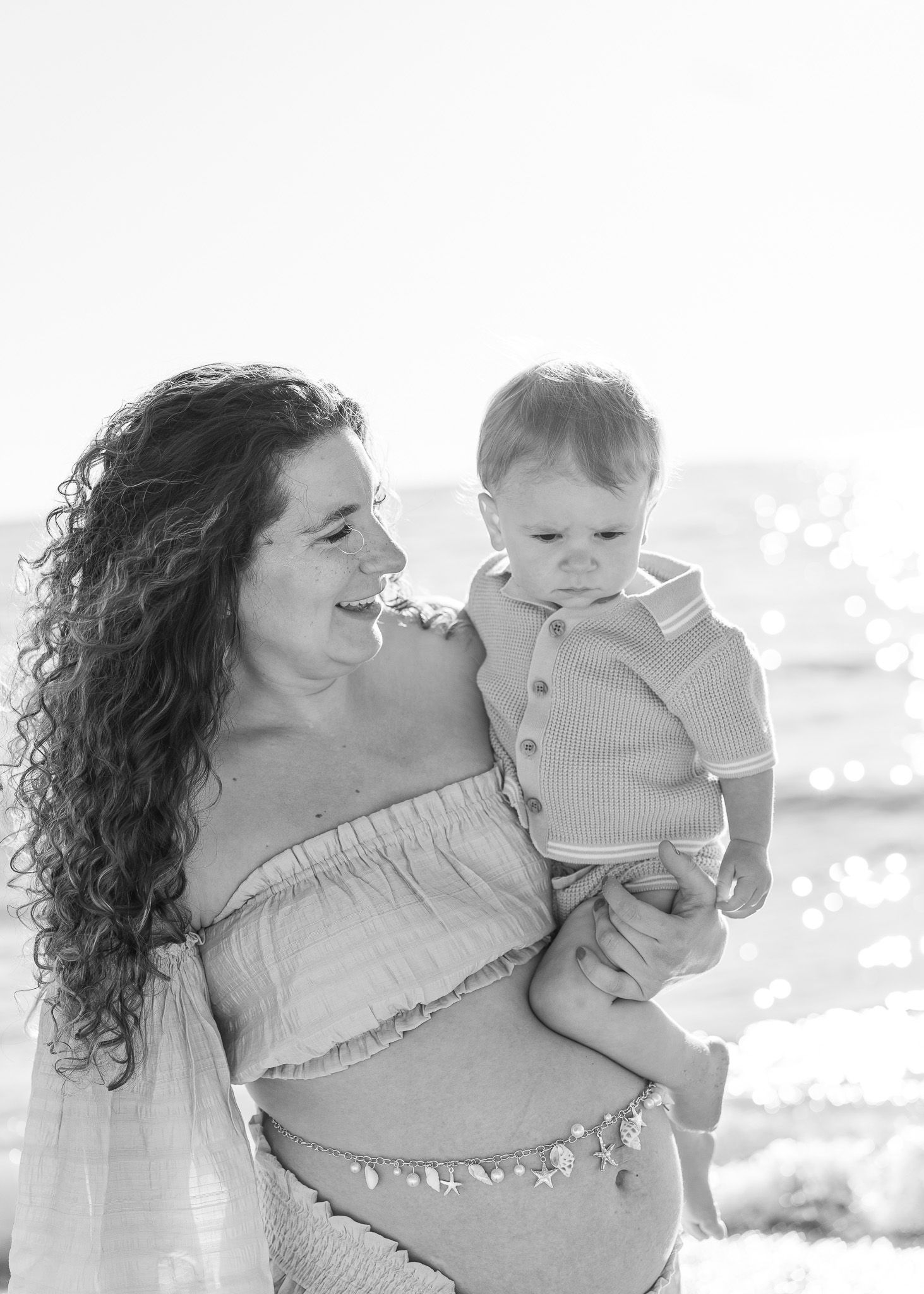 A series of black and white photos showing a mother and baby sharing tender moments together outdoors.