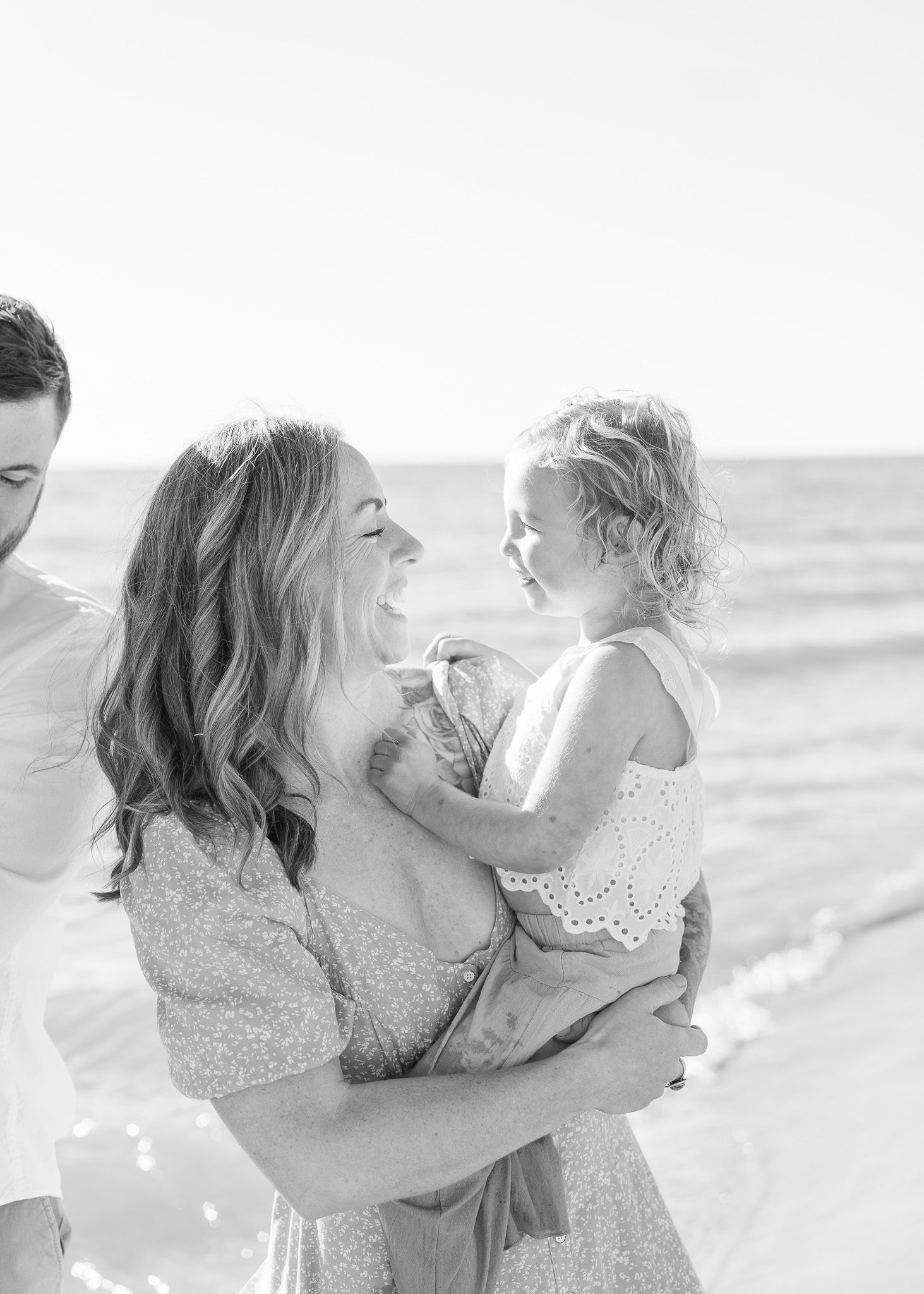 A tender moment between family members sharing laughter and joy together on a sunny beach.