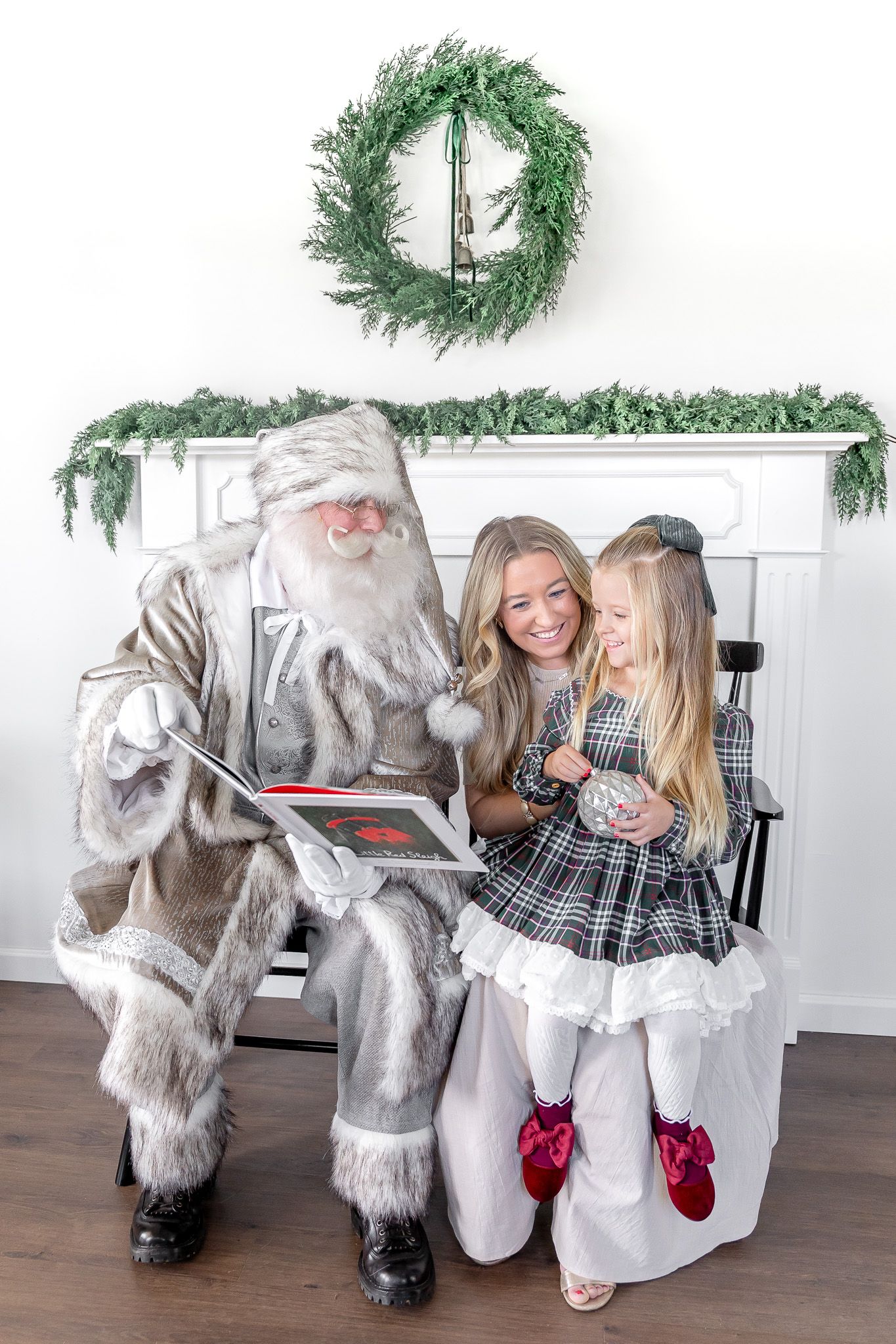 Holiday photo setup with black bench, fur blankets and evergreen garland.