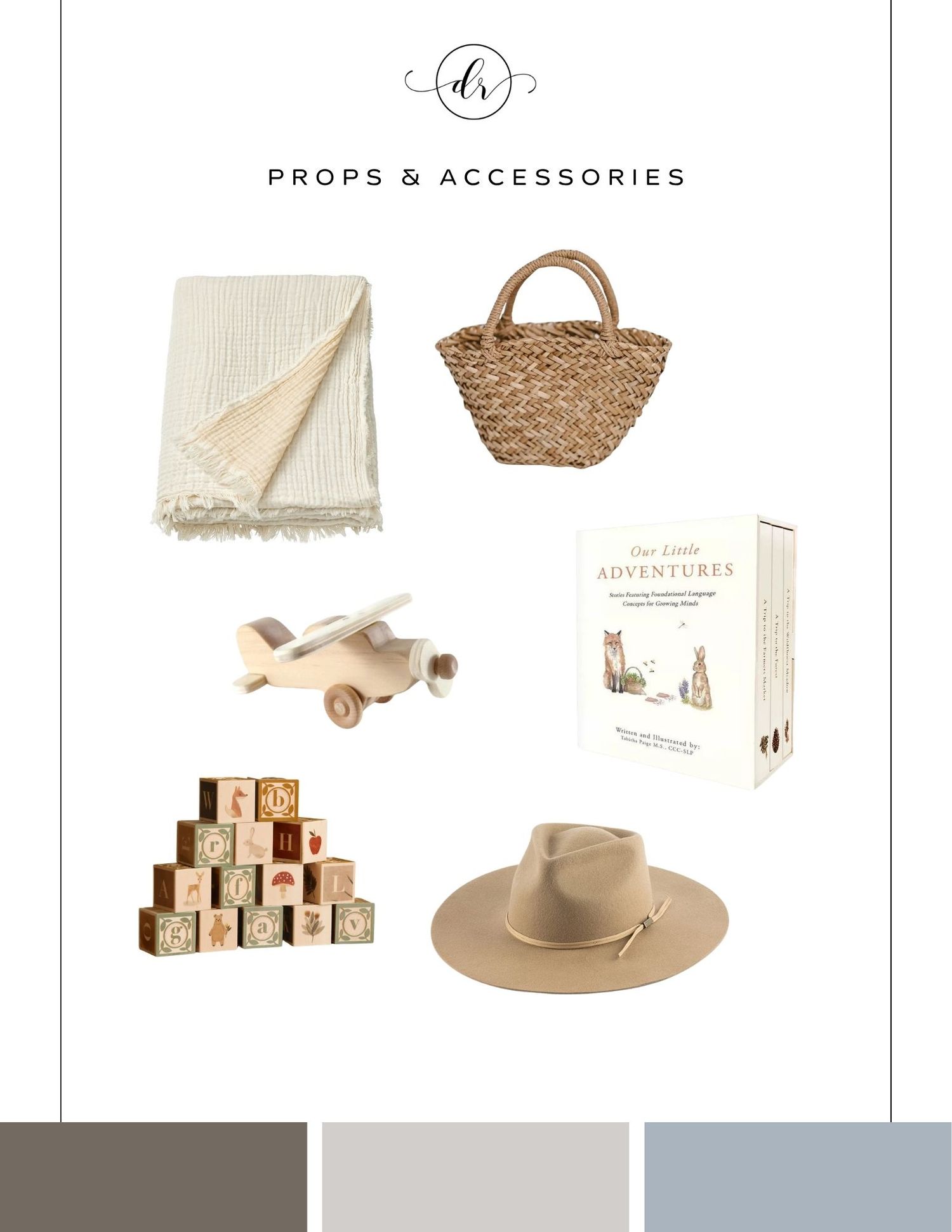 A flat lay of neutral-toned props including a knit blanket, wicker bag, toy plane, alphabet blocks, adventure book set, and wide-brim hat.