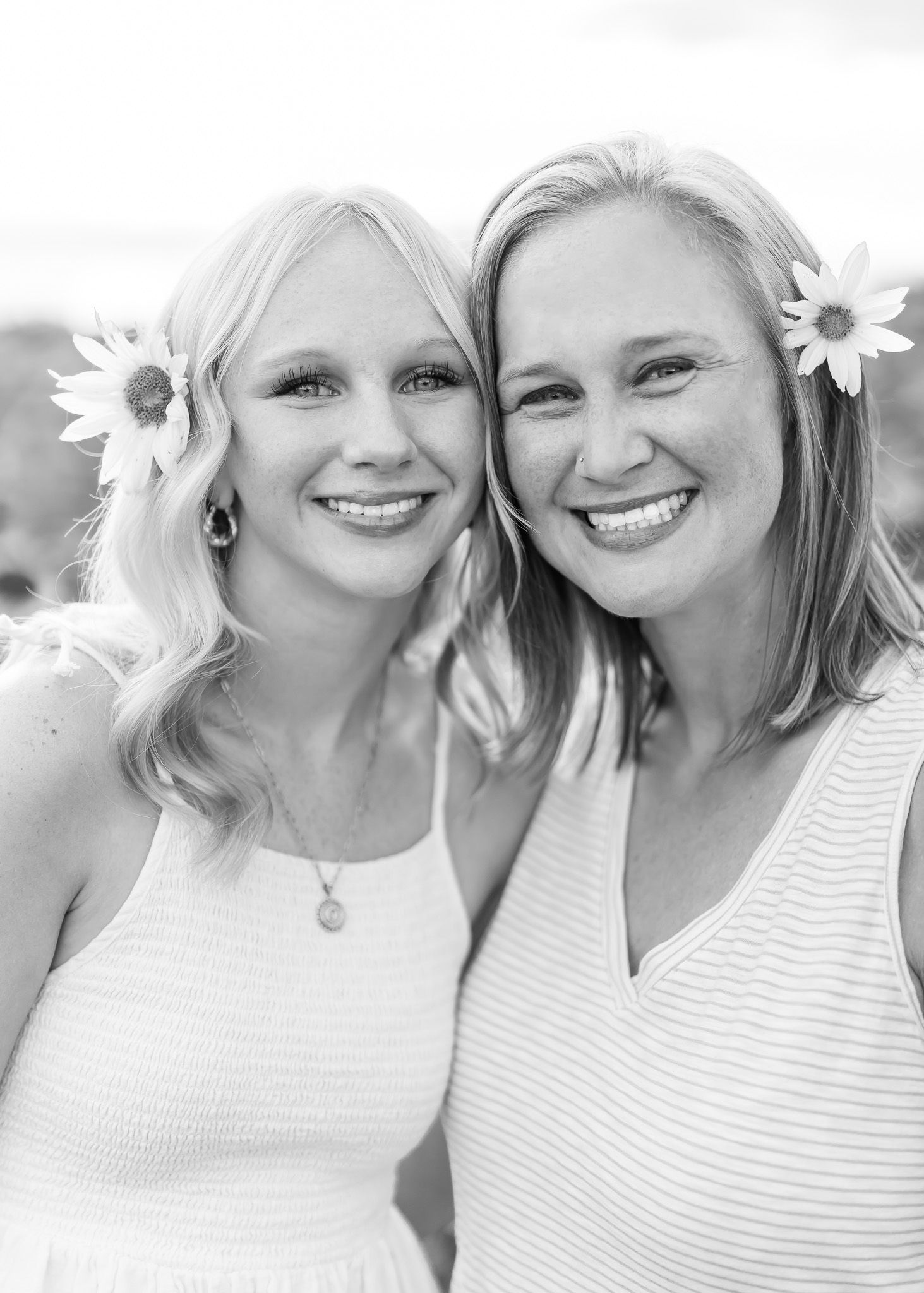 A series of black and white photos showing two people posing with white daisies in their hair and wearing striped tops.