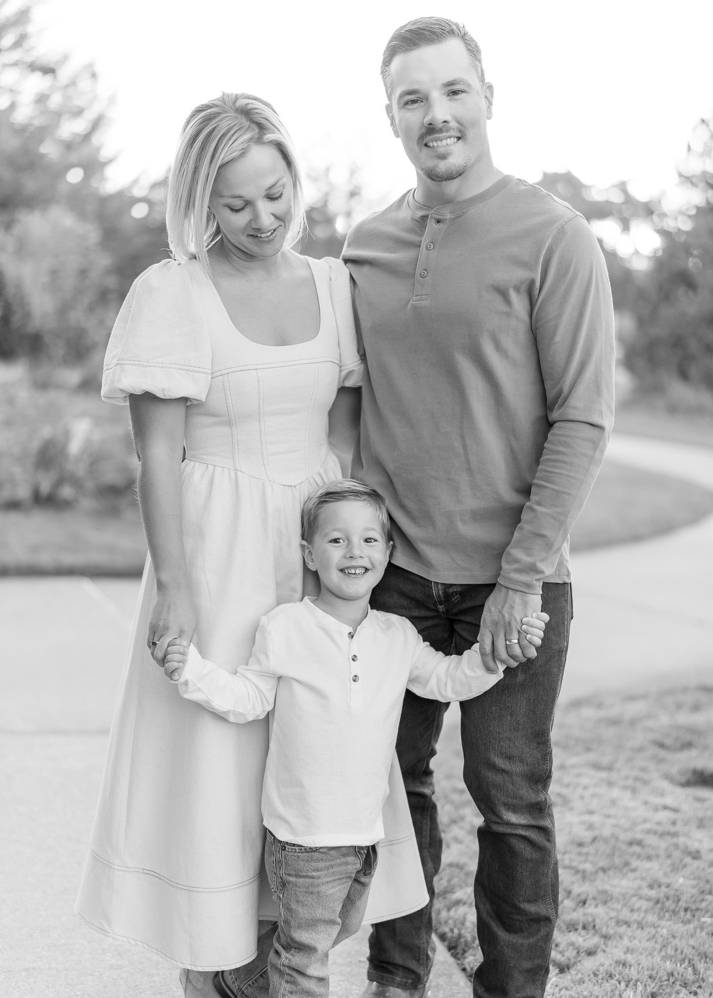 A family of three poses together outdoors in a series of black and white candid photos.