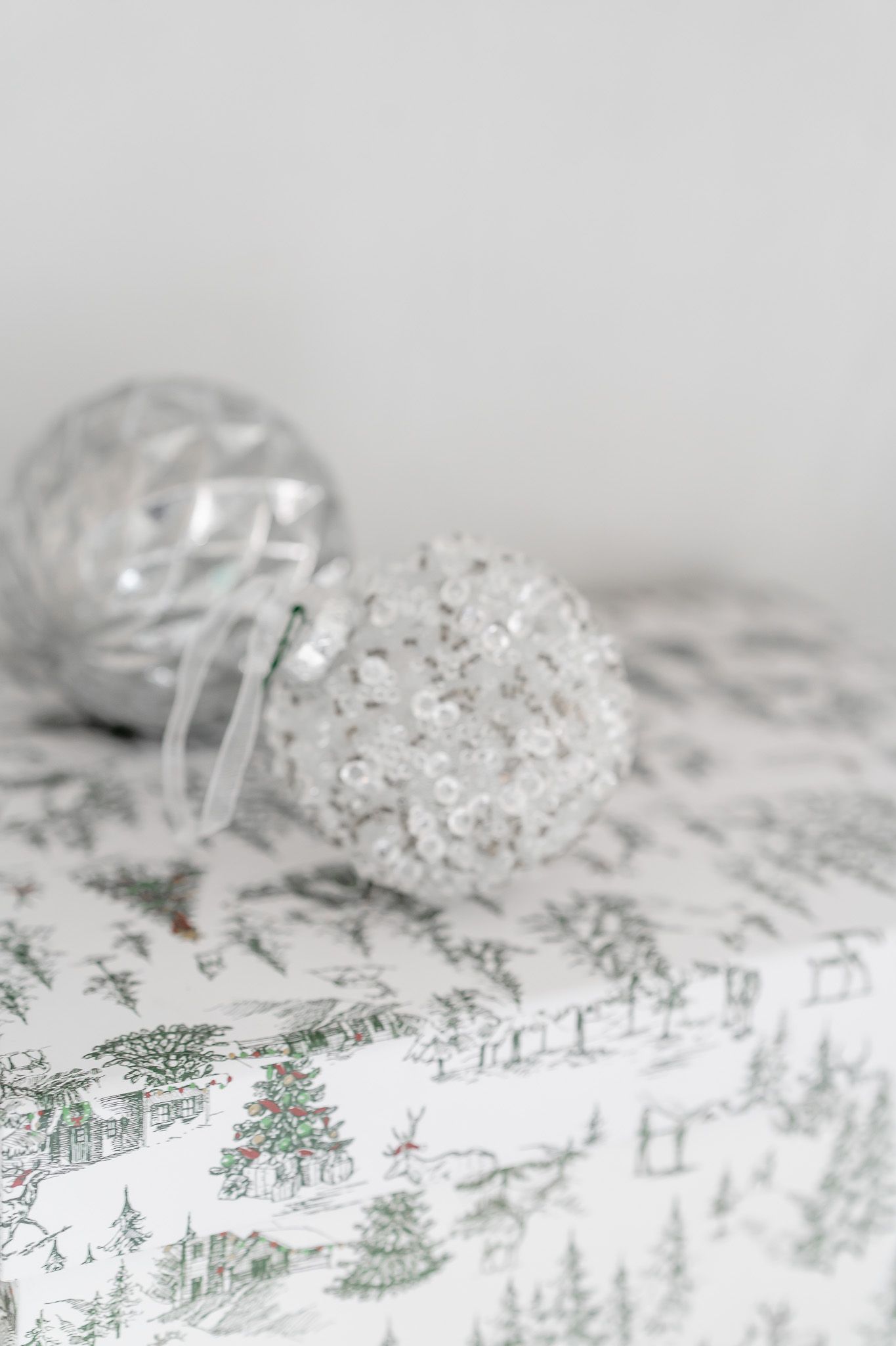 White winter-themed wrapping paper with delicate snowflakes and evergreen trees creates a festive holiday pattern.