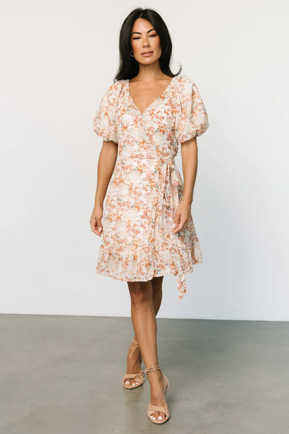Peach floral wrap dress with flutter sleeves shown against white background.