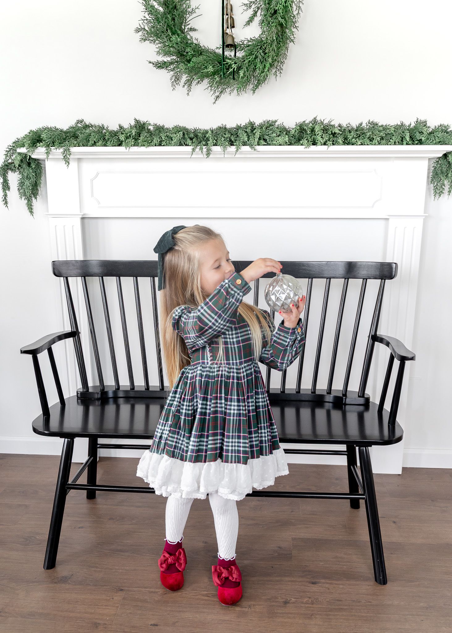 Black wooden bench decorated with evergreen garland and holiday accents.