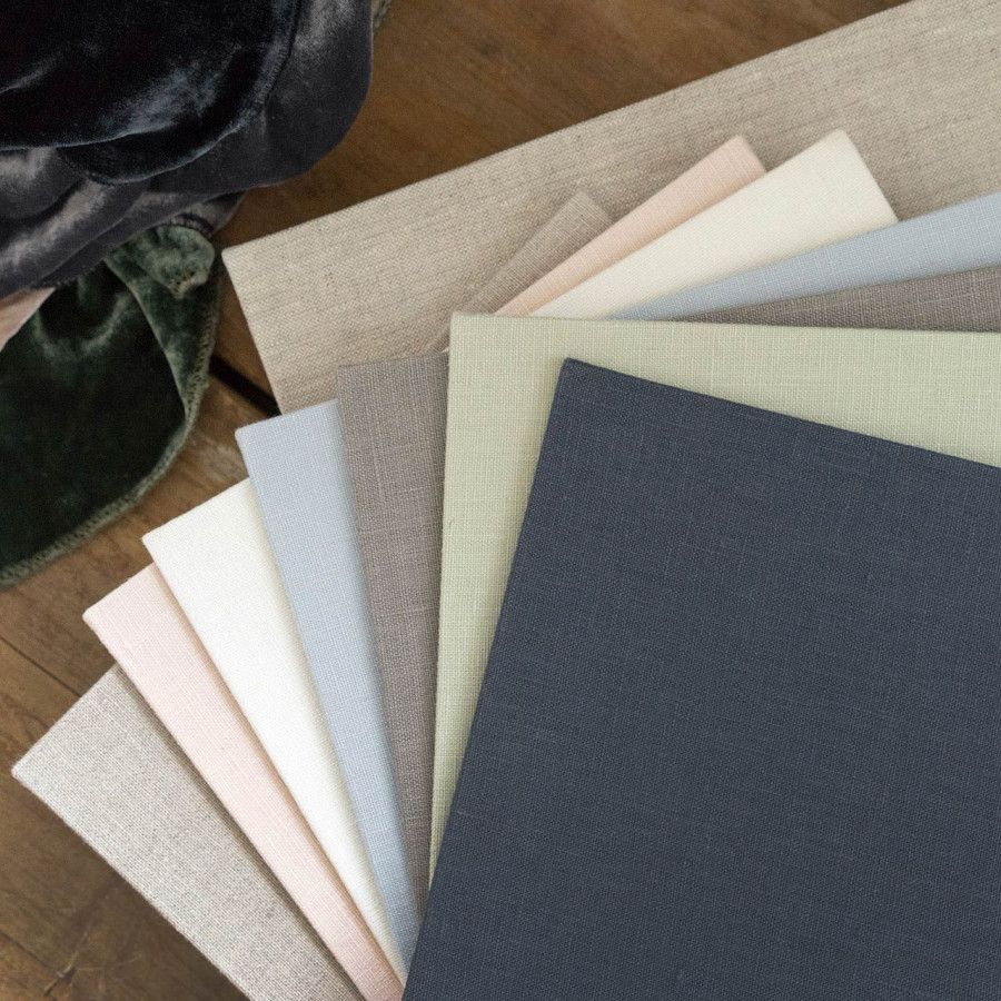 Multiple paper or fabric swatches arranged in a gradient from light to dark colors displayed on a wooden surface.