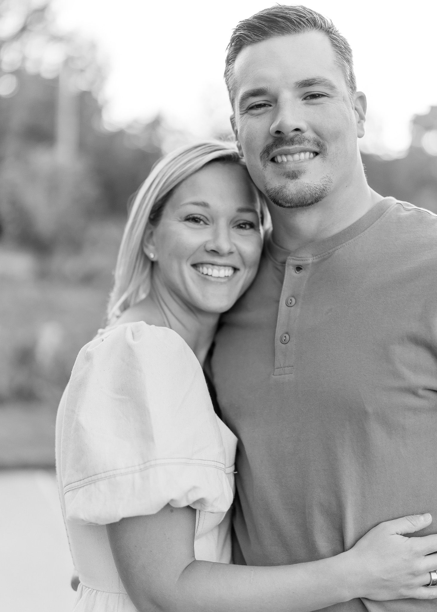 A romantic black and white photo series showing a couple embracing and smiling together outdoors.