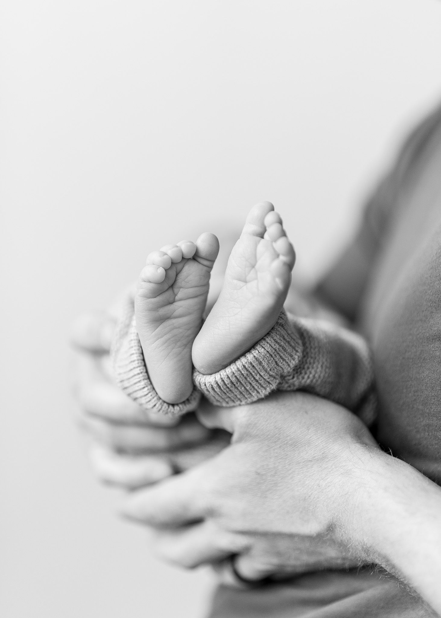 A series of four black and white images showing tiny baby feet resting on an adult's palm.