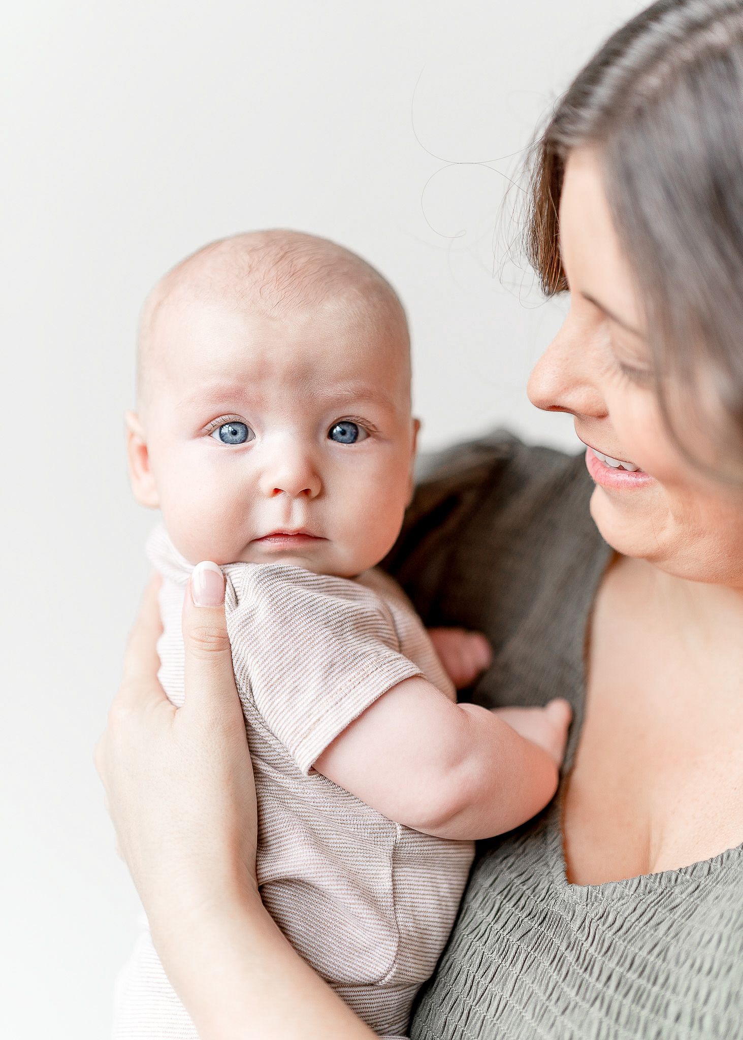 A parent holds a baby wearing a light gray onesie in a series of tender moments captured in multiple photos.