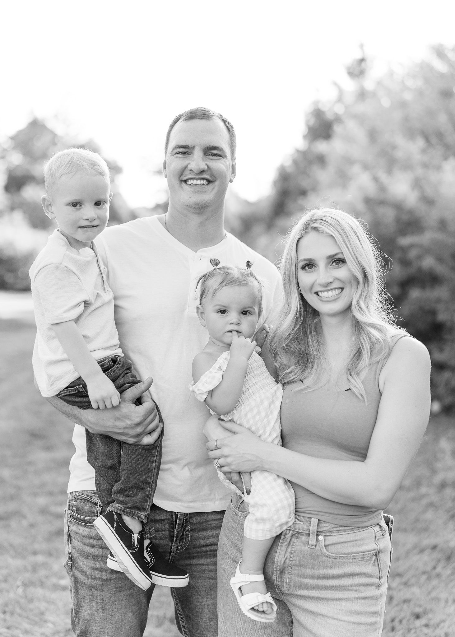 A family in casual attire poses together outdoors in black and white photos showing candid moments and smiles.