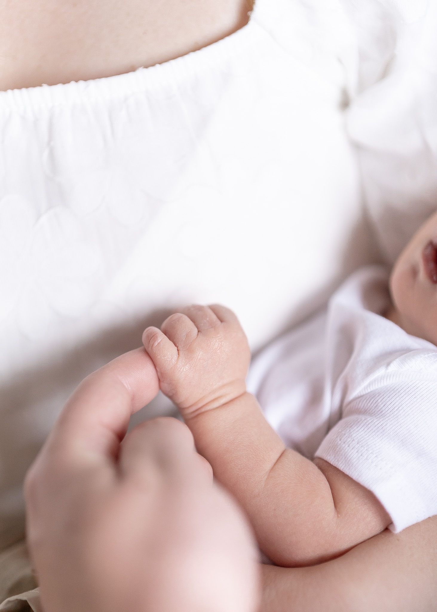 Sleeping newborn baby wearing white clothing rests peacefully in soft blankets.