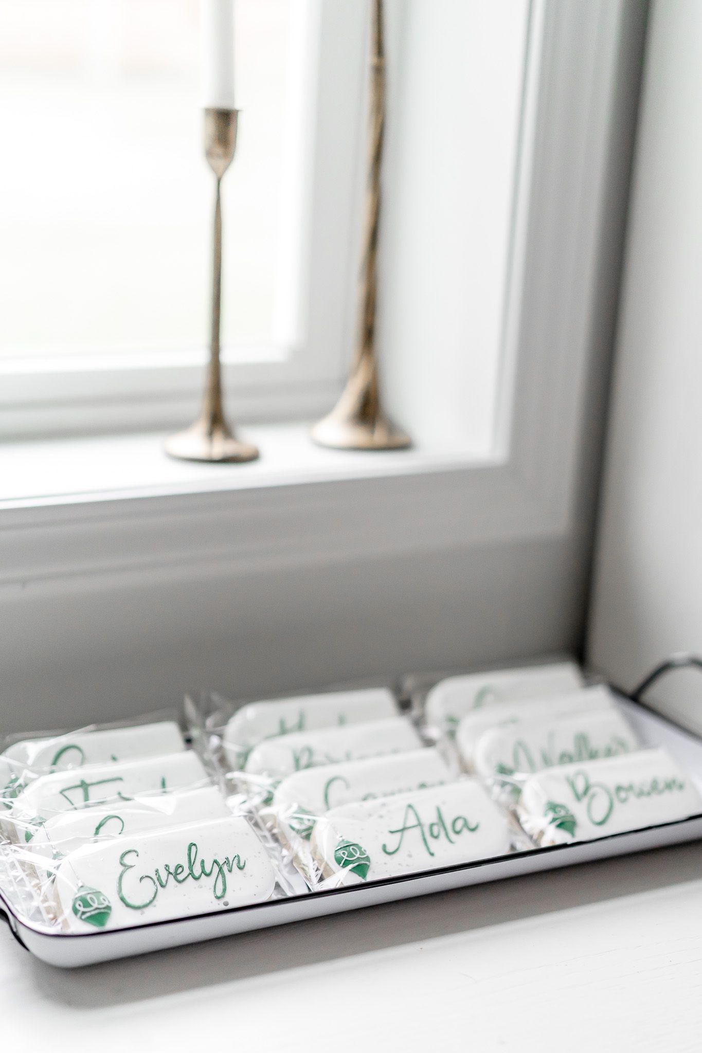 Personalized place cards with green calligraphy names arranged on a white tray.