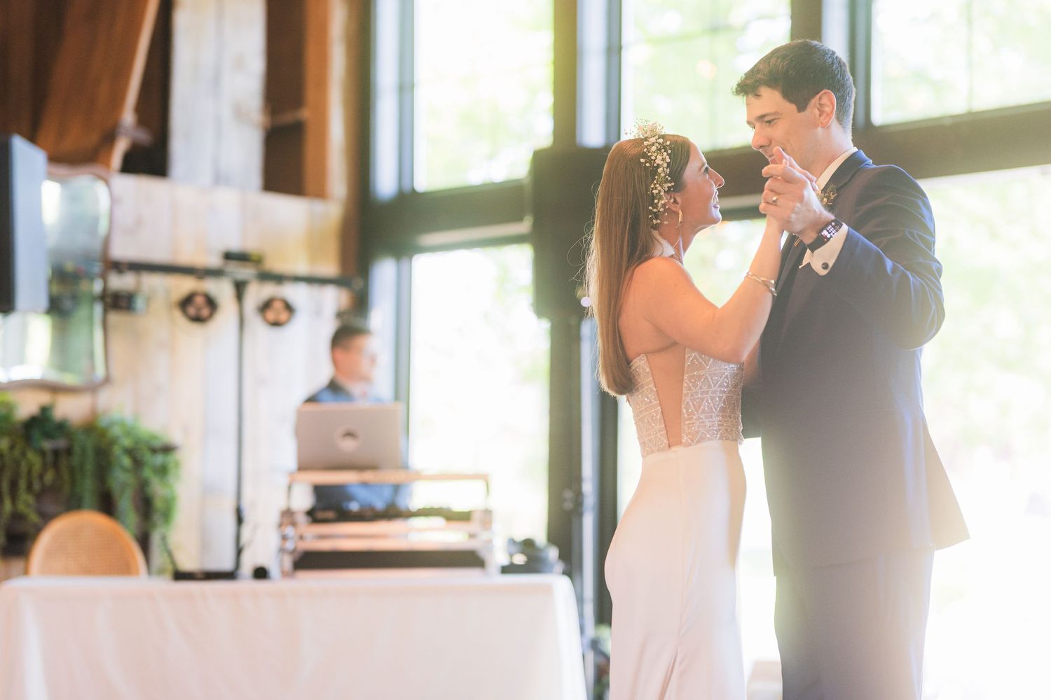 Couple dancing together at an elegant indoor wedding reception with natural light streaming through windows.
