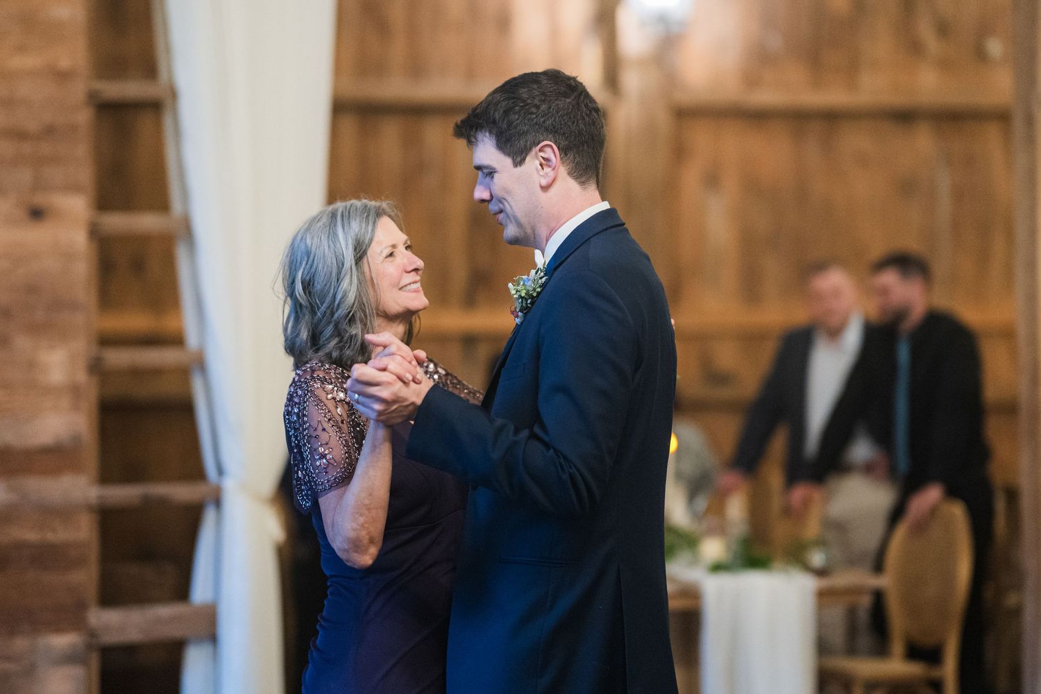 A couple dancing together in an elegant rustic barn venue.