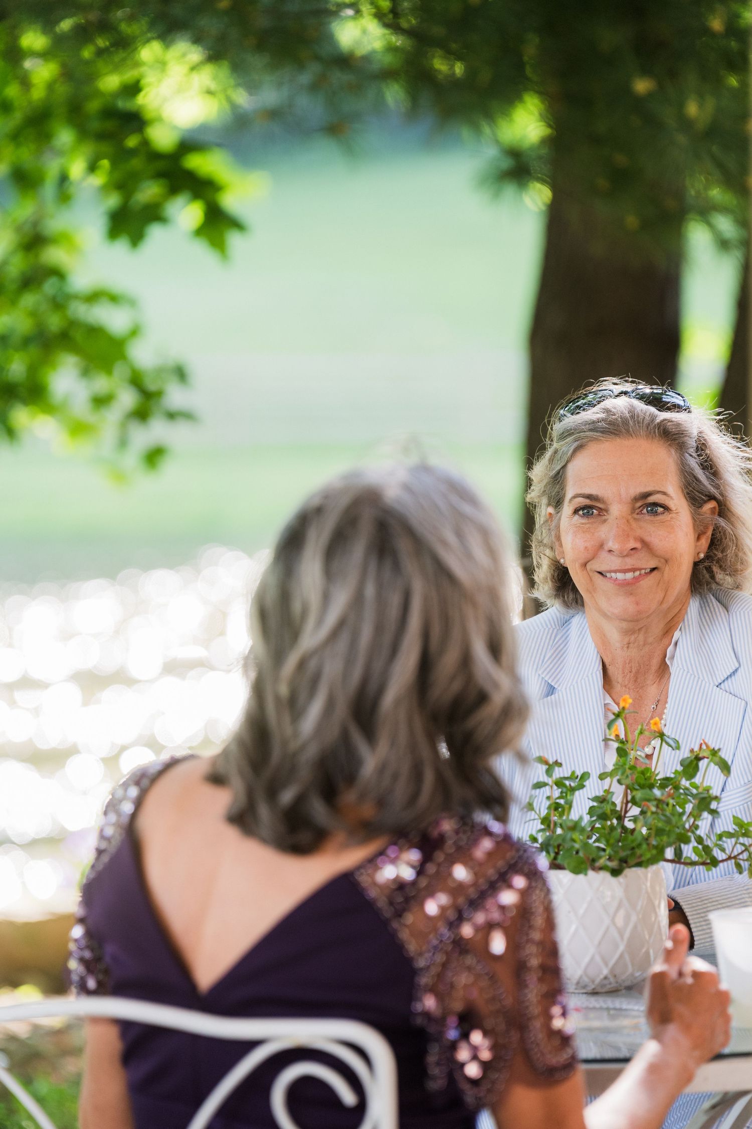 Two guests share conversation at an outdoor garden wedding reception table.